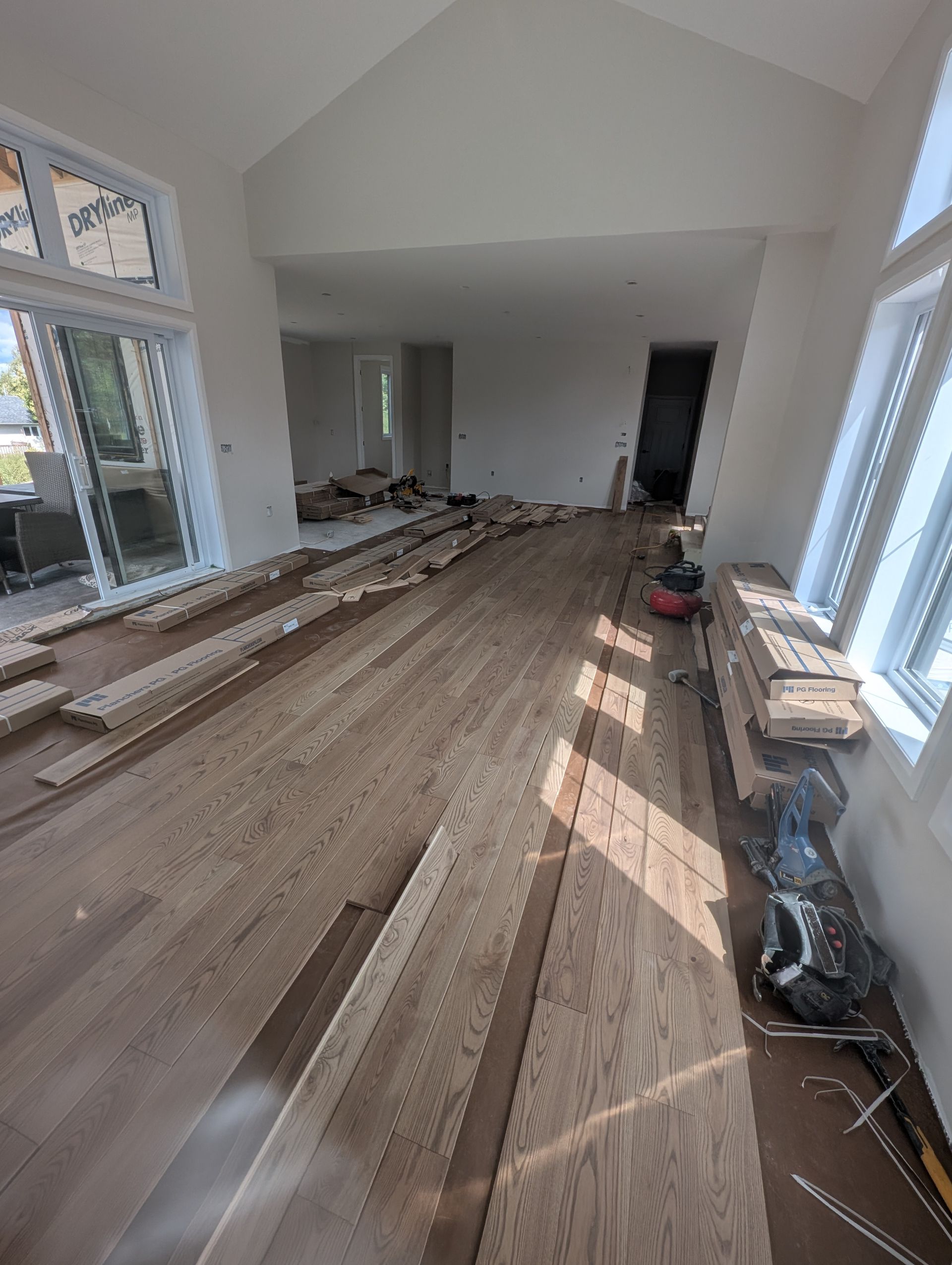 Pièce intérieure en travaux, pose de parquet en cours, lumière naturelle et porte ouverte.