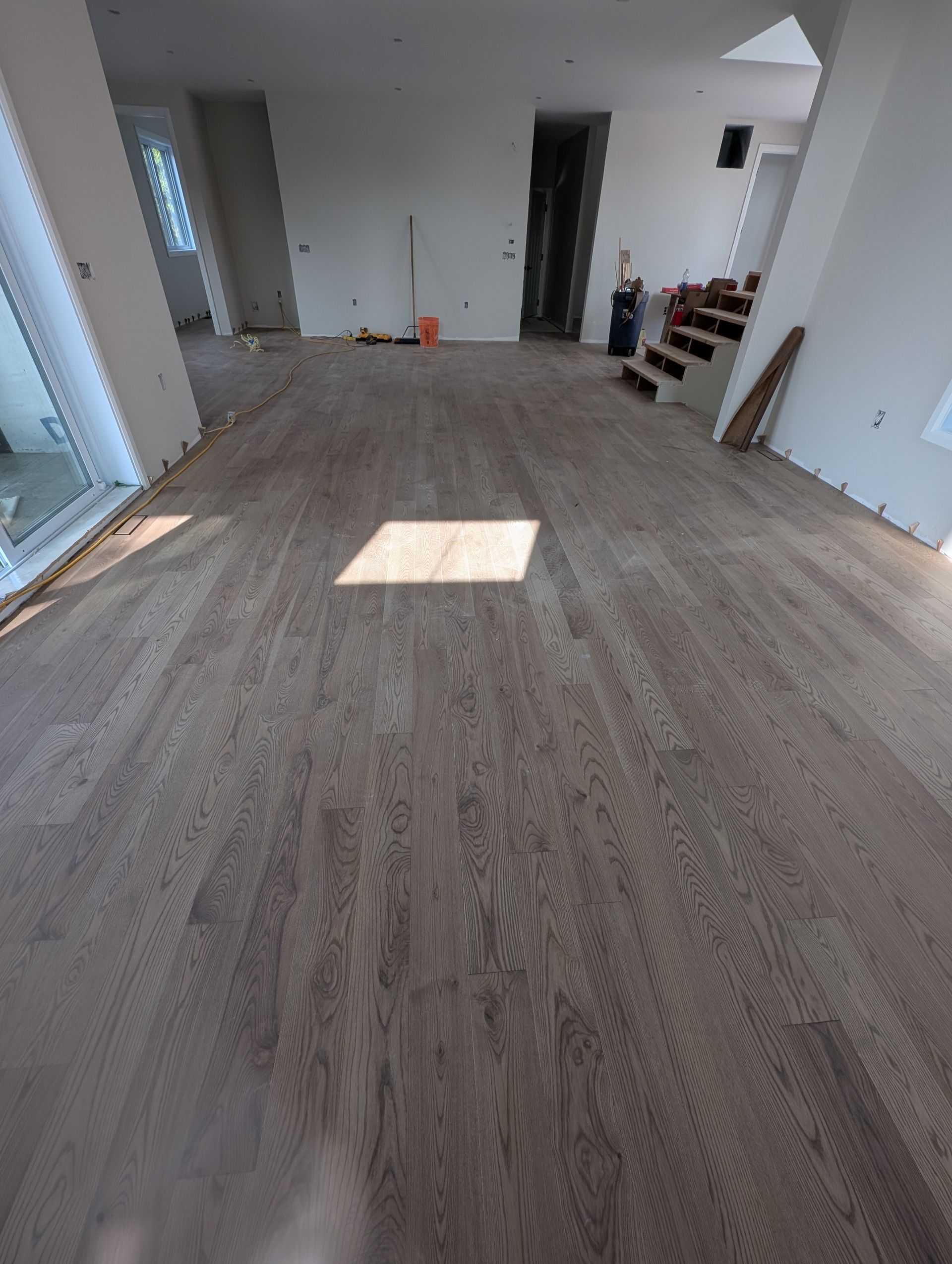 Plancher en bois franc brun clair nouvellement installé dans une pièce vide, avec des murs non finis.