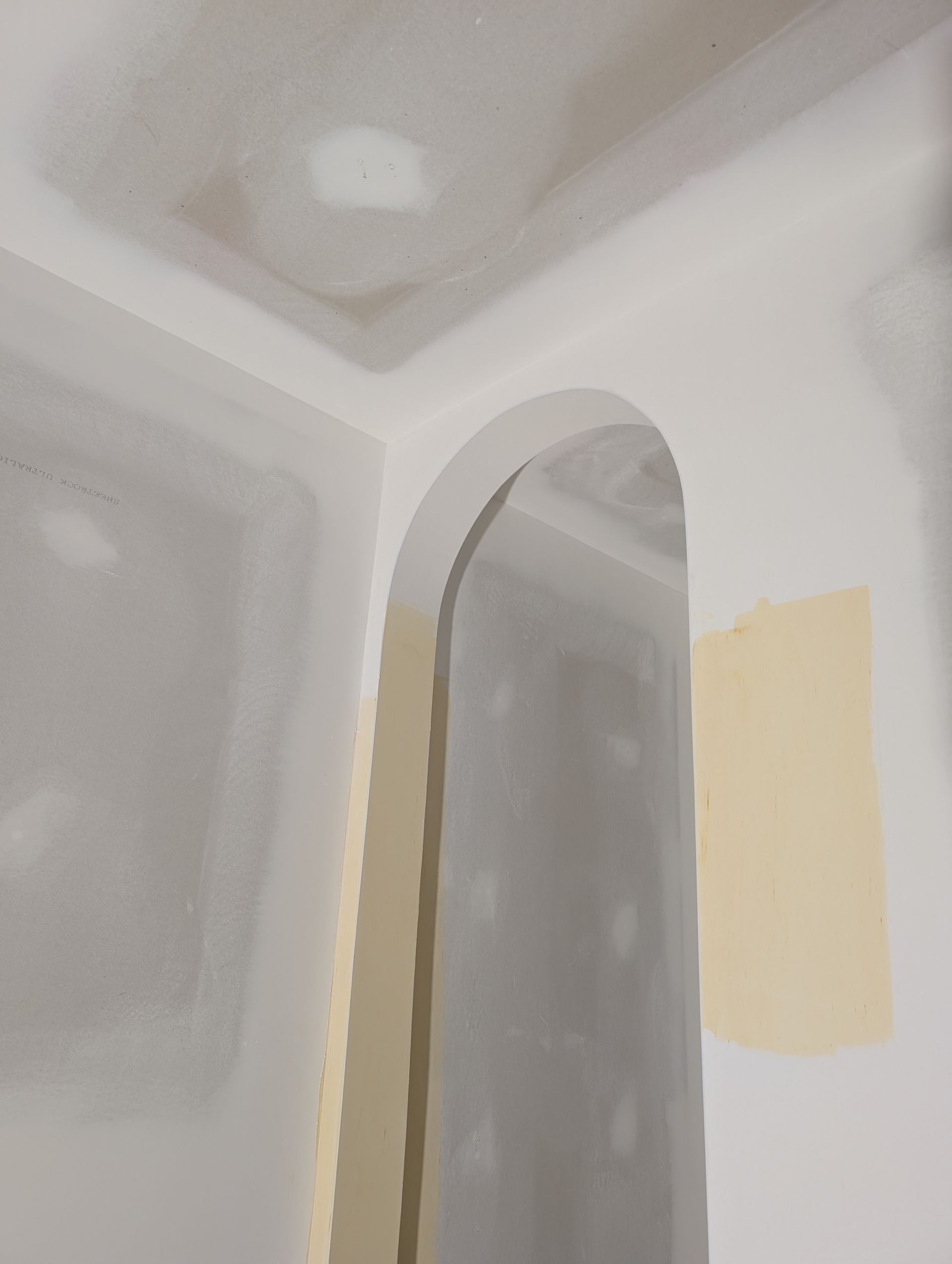 Angle intérieur avec porte cintrée et cloison sèche partiellement finie.