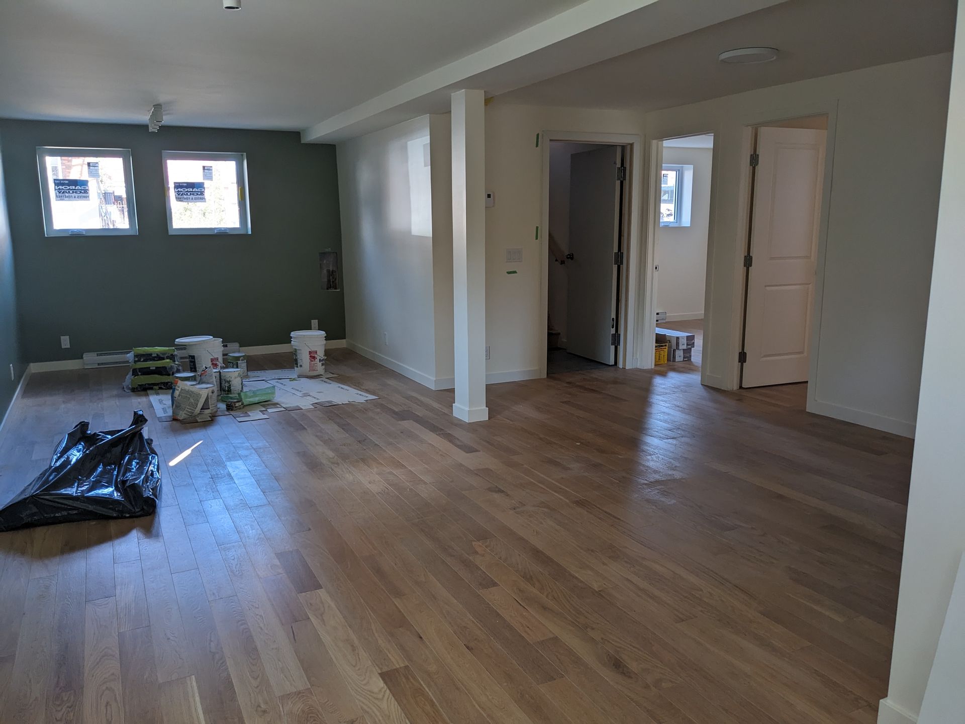Intérieur récemment rénové avec parquet, murs blancs et un mur d'accent vert.