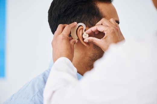 Doctor examining a patient's ear with an otoscope in a bright clinic