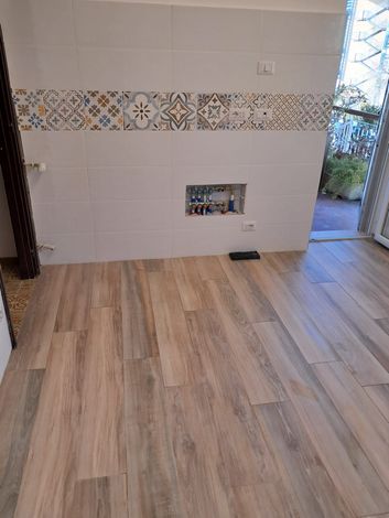 Cucina moderna con isola blu navy, mobili in legno chiaro, sgabelli e finestre luminose.