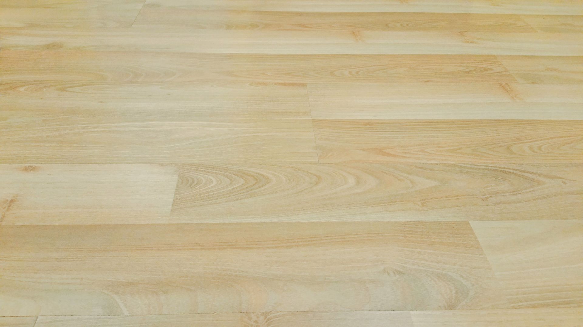 Light-colored wooden floor with subtle grain patterns and horizontal plank seams