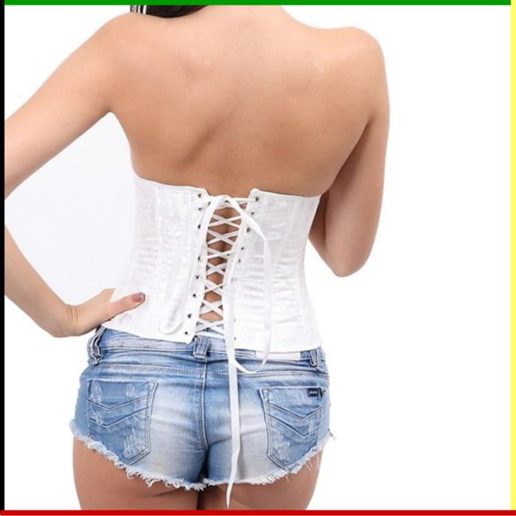 Witte corset over een spijkerbroekje, handen over de borst.