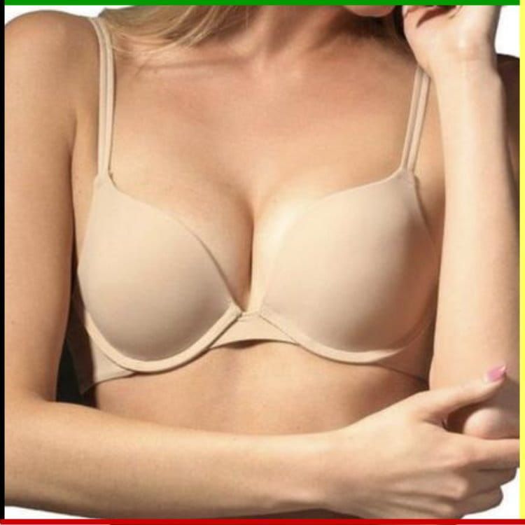Vrouw met een beige push-up bh aan, arm gebogen, hand bij het gezicht.