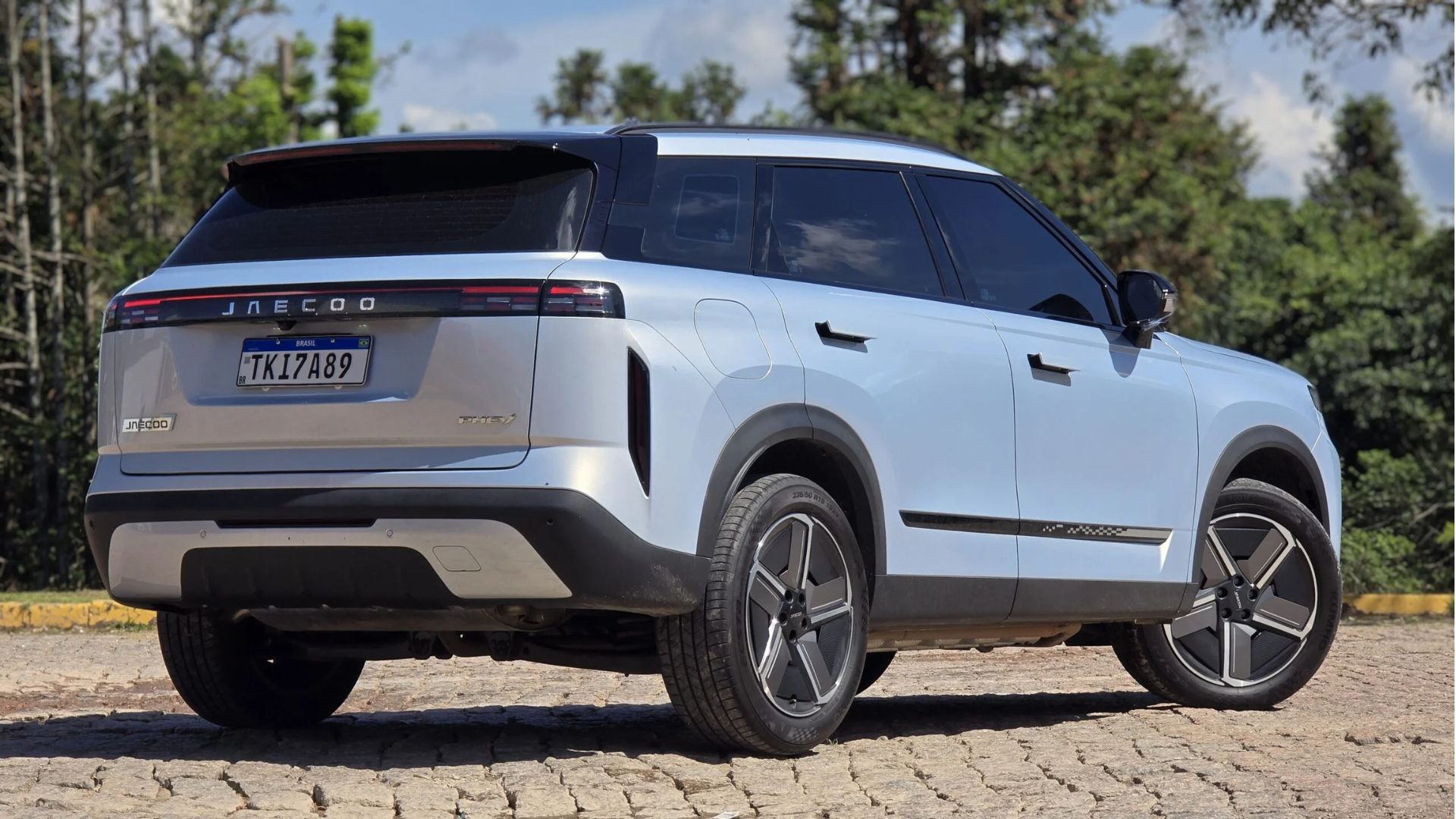Silver SUV parked on a cobblestone road with trees in the background
