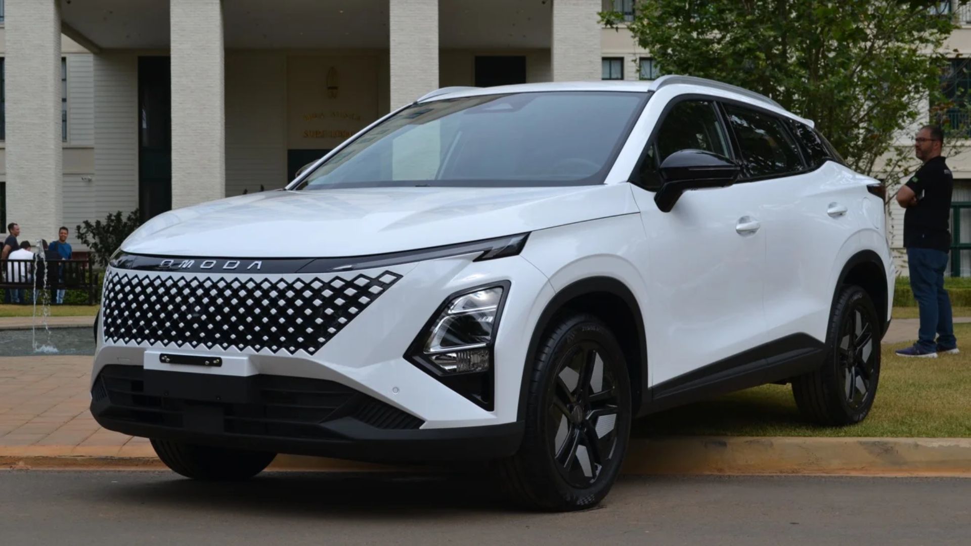 White SUV parked outdoors near a building, with a person standing beside it.