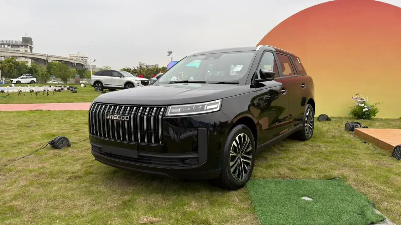 Black SUV displayed on grass outdoors with an orange backdrop and cloudy sky
