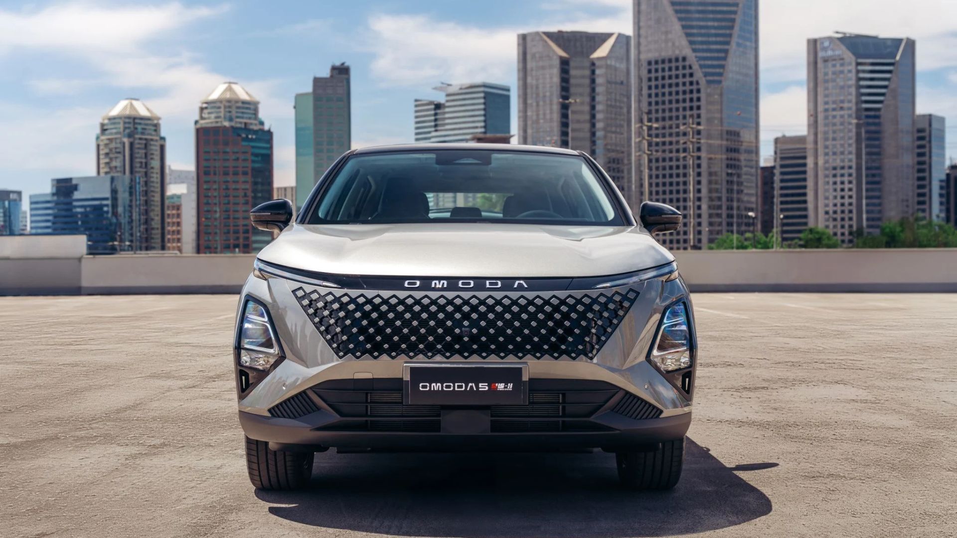 Front view of a silver SUV parked before a city skyline and waterfront