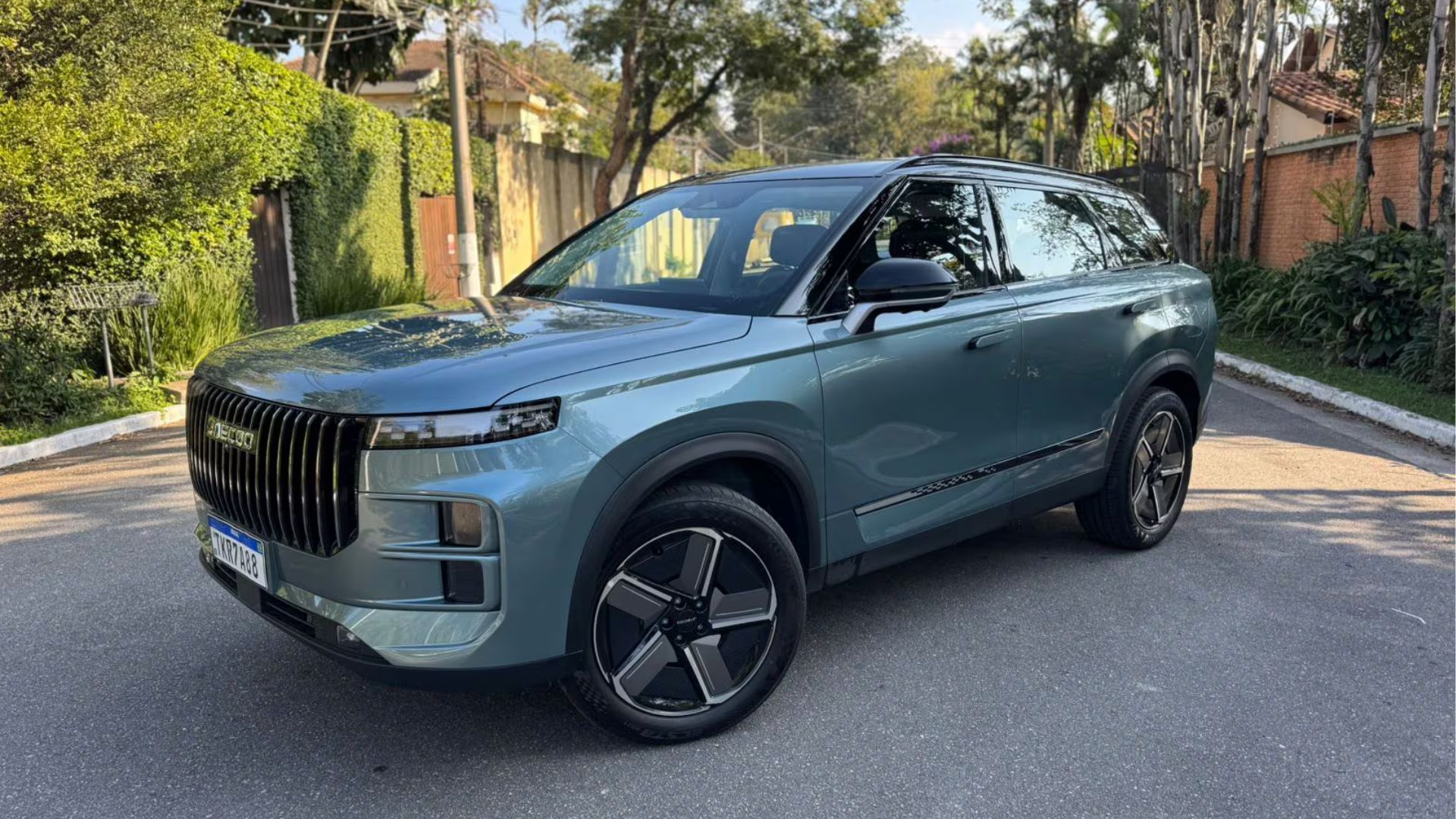 Blue-gray SUV parked on a sunny street with trees and houses in the background