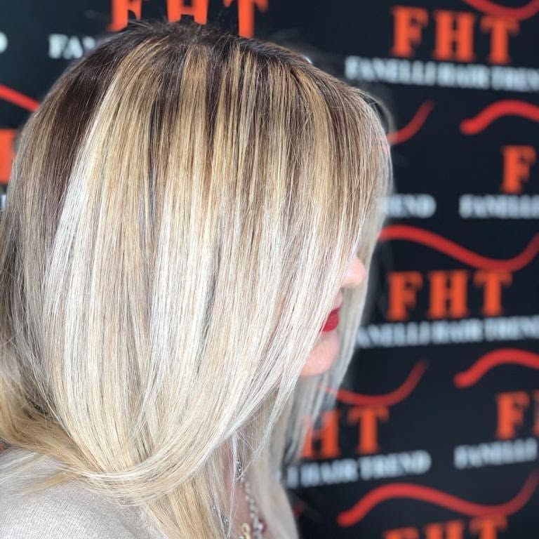 Capelli biondi con radici scure raccolti in una coda bassa su uno sfondo FHT