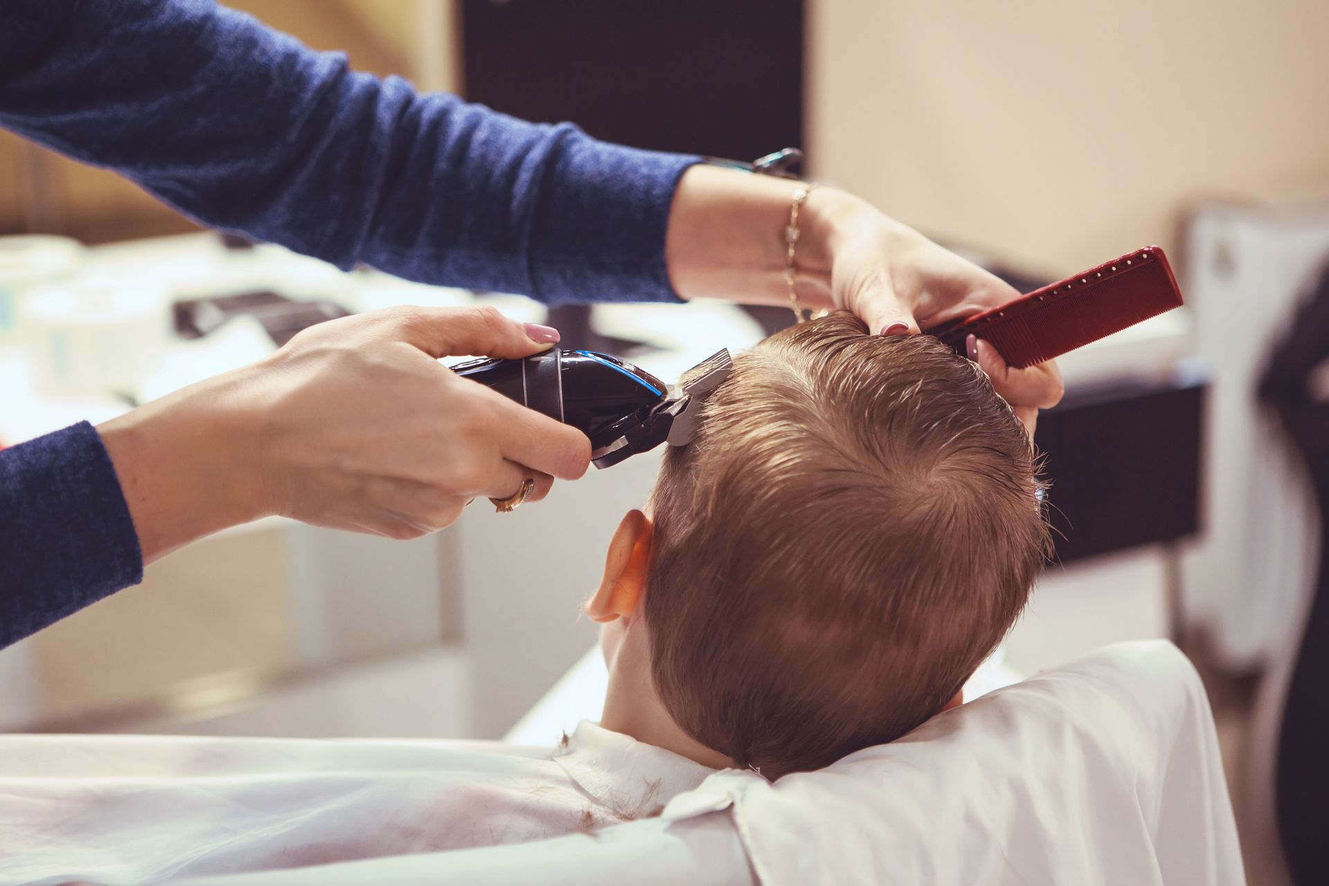 I capelli vengono tagliati con il rasoio elettrico mentre un pettine tiene ferme le ciocche sulla poltrona del barbiere.