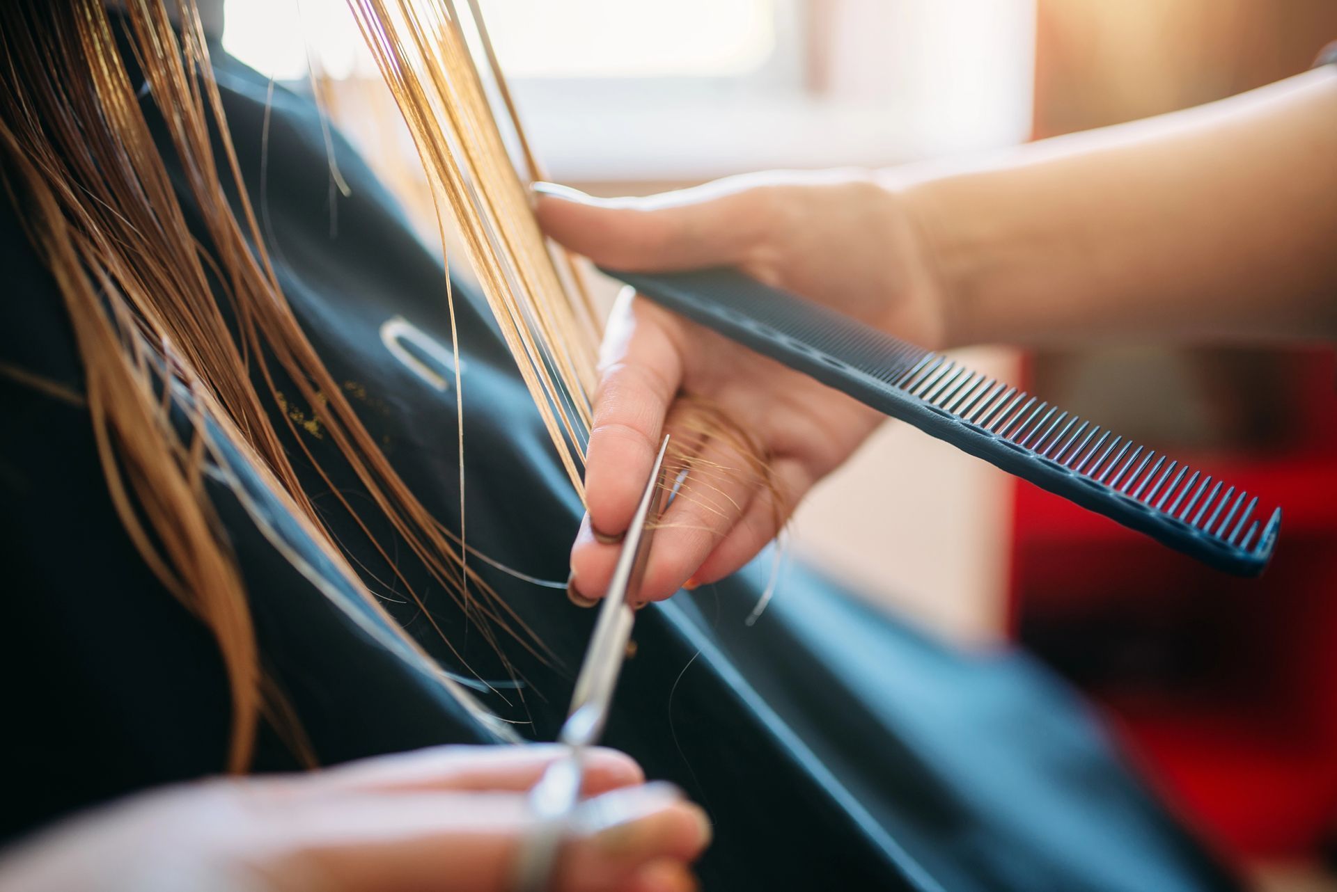 Parrucchiere che taglia capelli lunghi con forbici e pettine in un salone