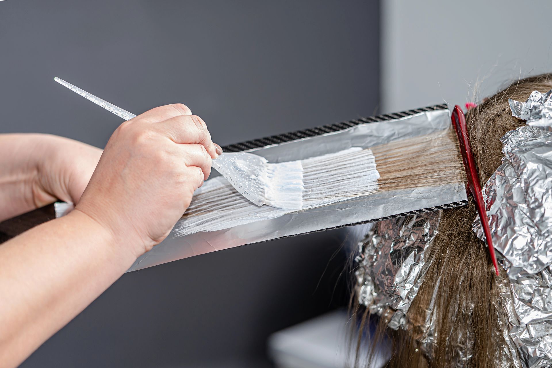Applicazione della tintura per capelli su capelli avvolti nella stagnola, secondo un procedimento tipico dei saloni di bellezza.
