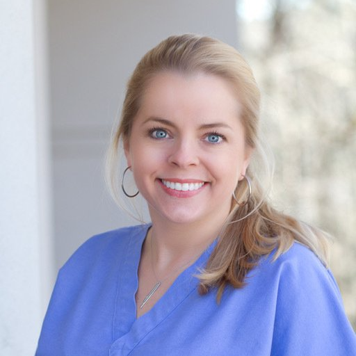 A woman in a blue scrub is smiling for the camera