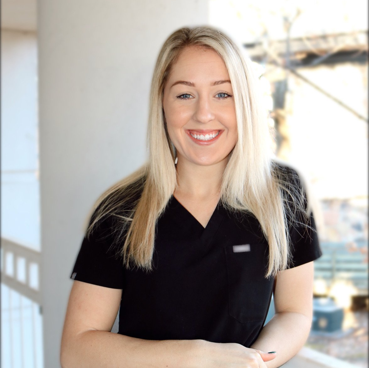 A smiling blonde woman wearing a black scrub top