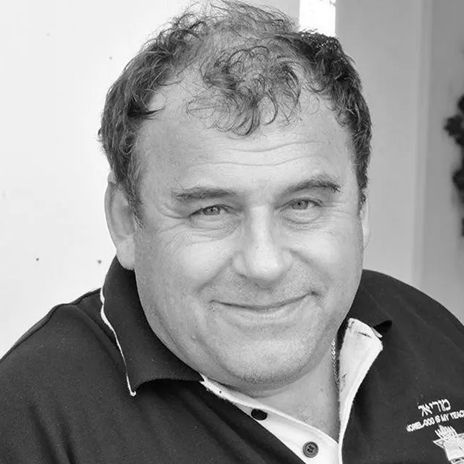 A man with curly hair is smiling in a black and white photo.