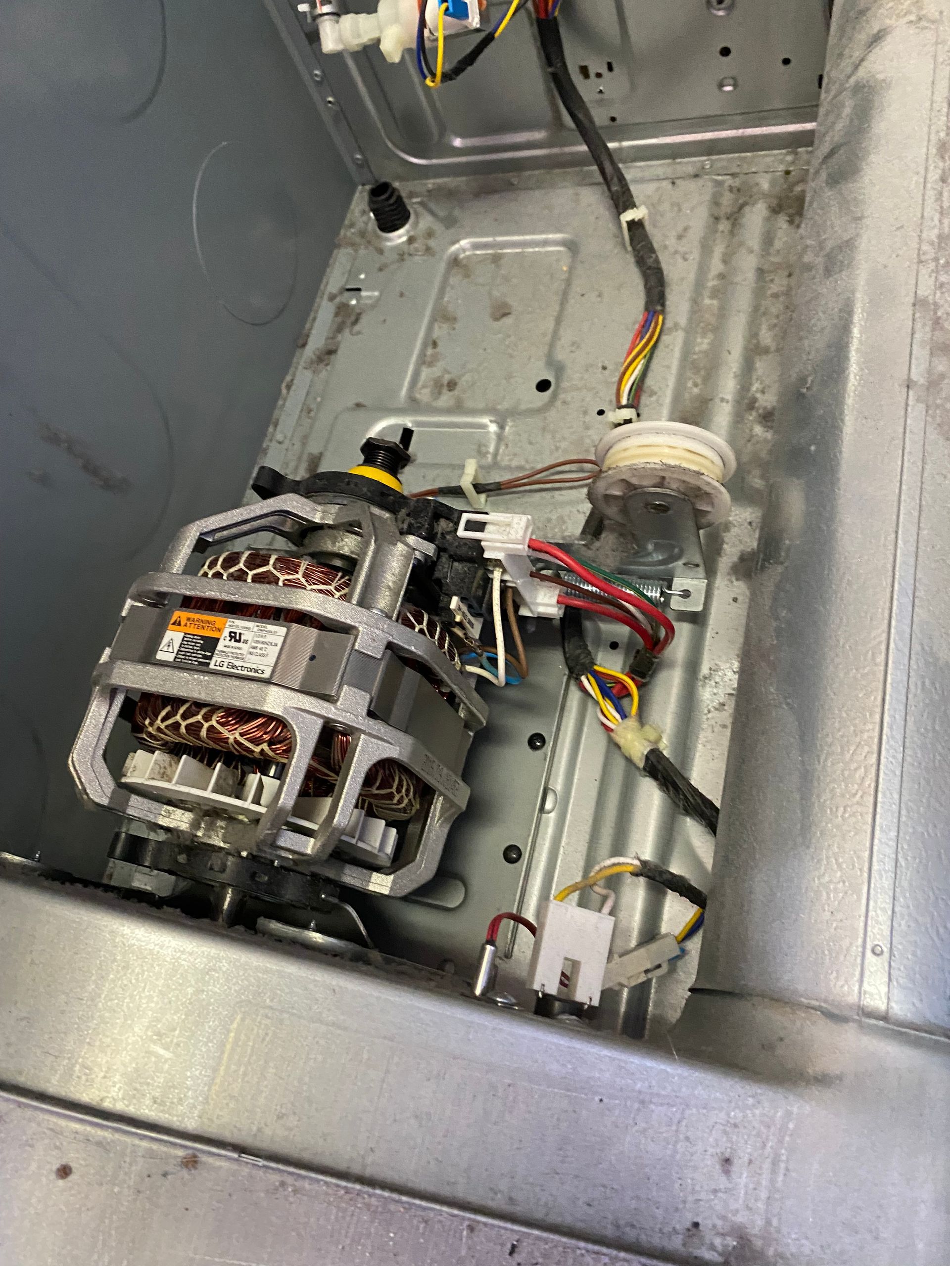 Interior view of a washing machine. Motor and wiring are visible.