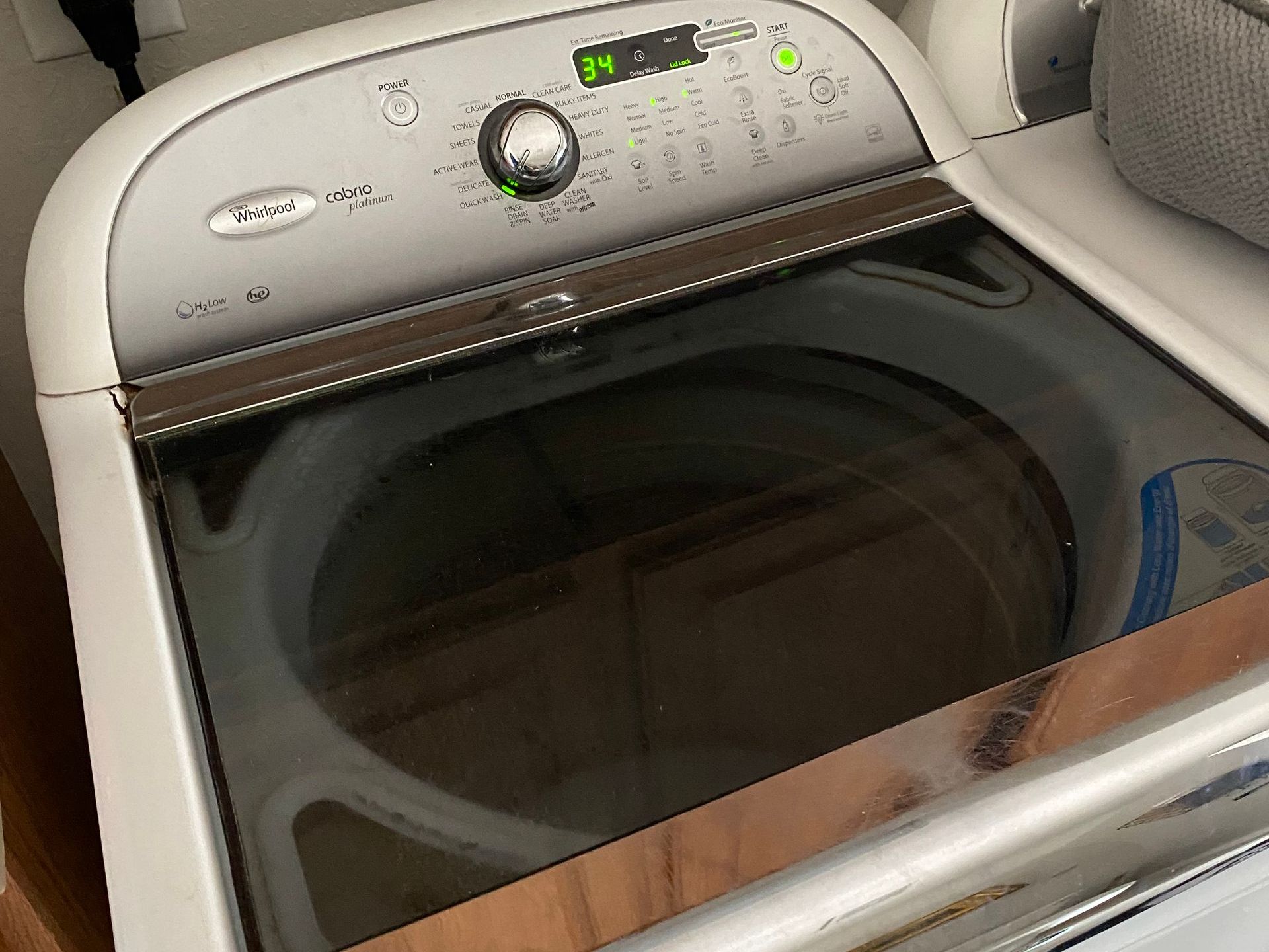 White Whirlpool dryer with dark glass door, control panel displays time remaining.
