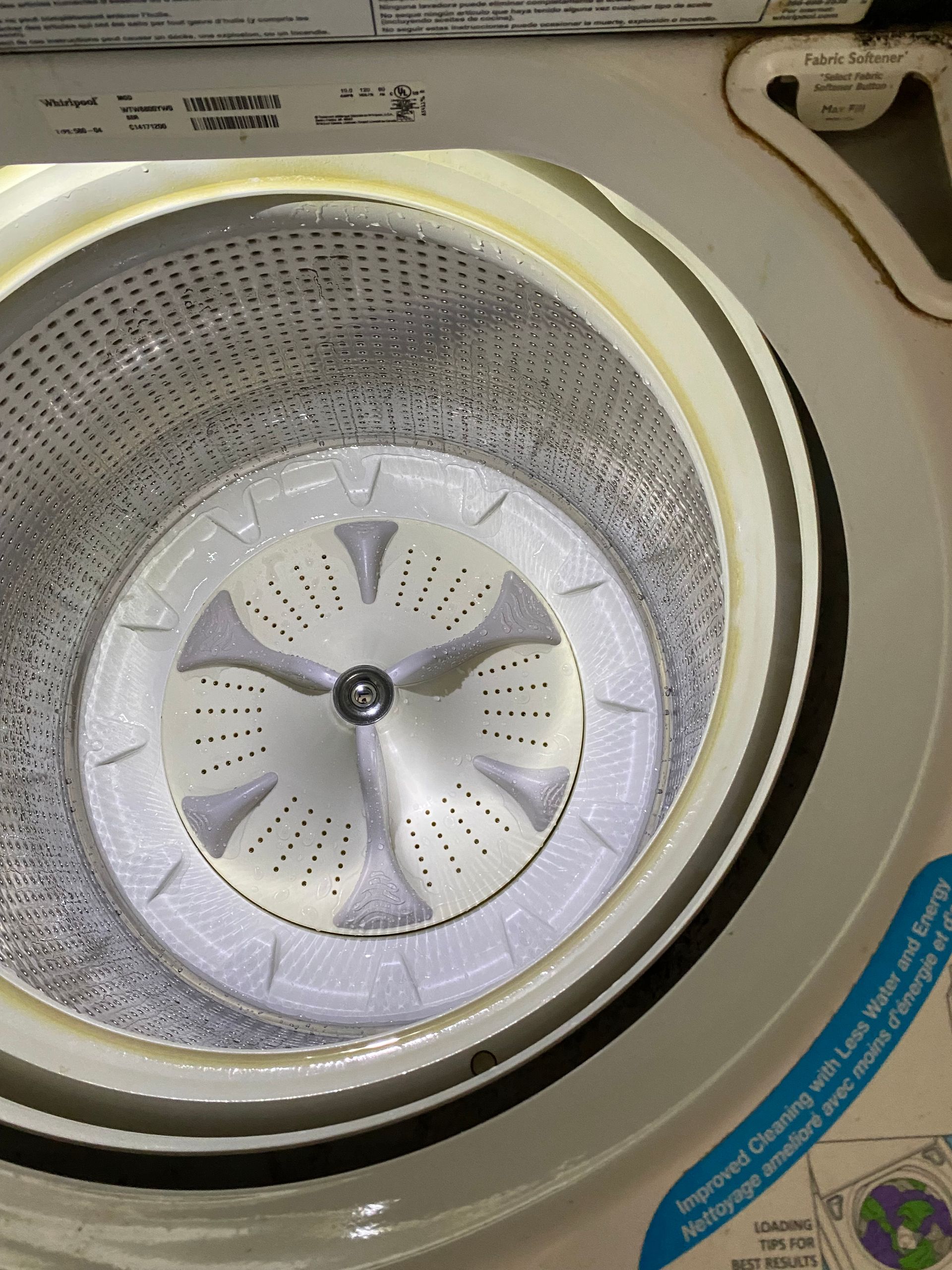 Inside view of a top-load washing machine drum, showing the wash basket with the agitator at the bottom.