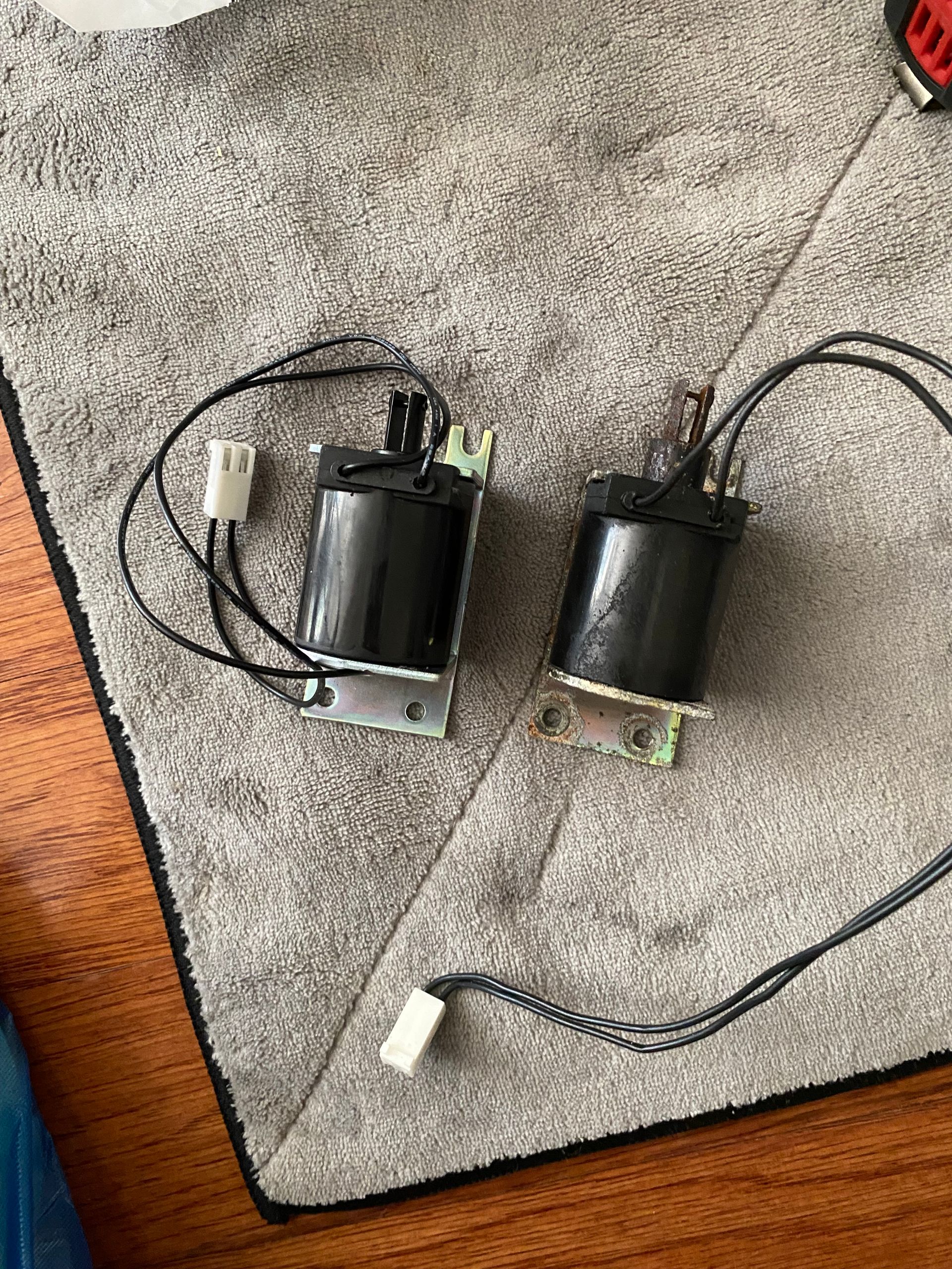 Two black solenoid valves with wiring on a gray surface.