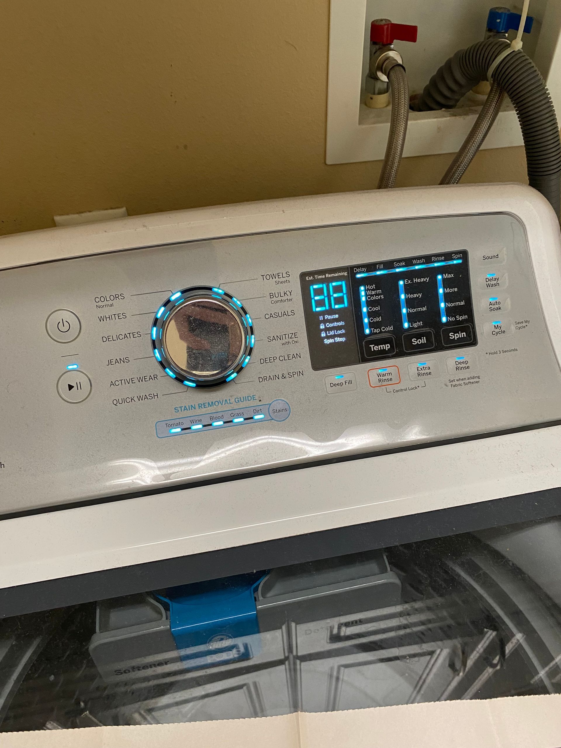 White washing machine control panel with blue lights and digital display.