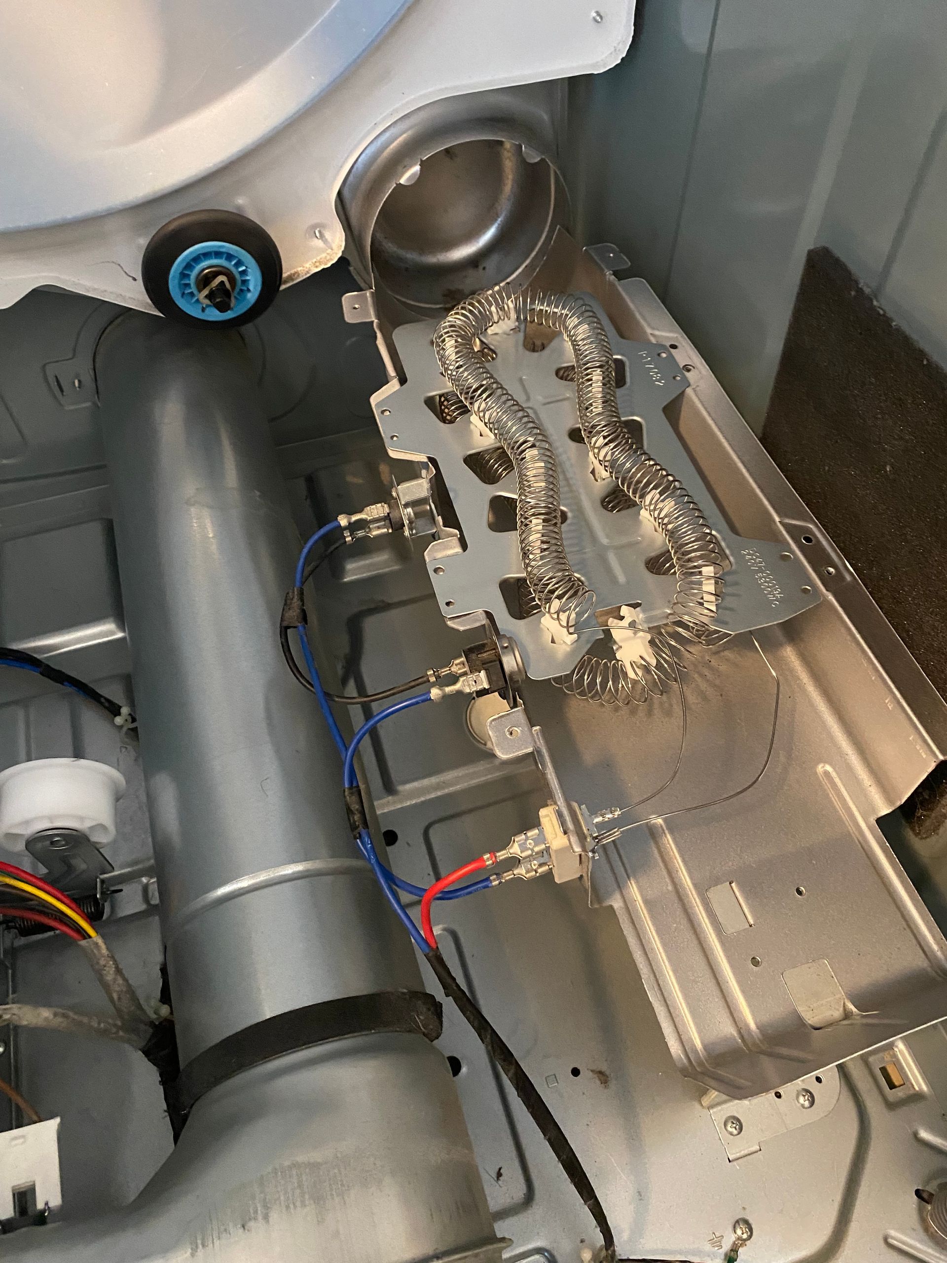 Interior of a dryer showing heating element, vents, and wiring. White and silver components against a gray background.