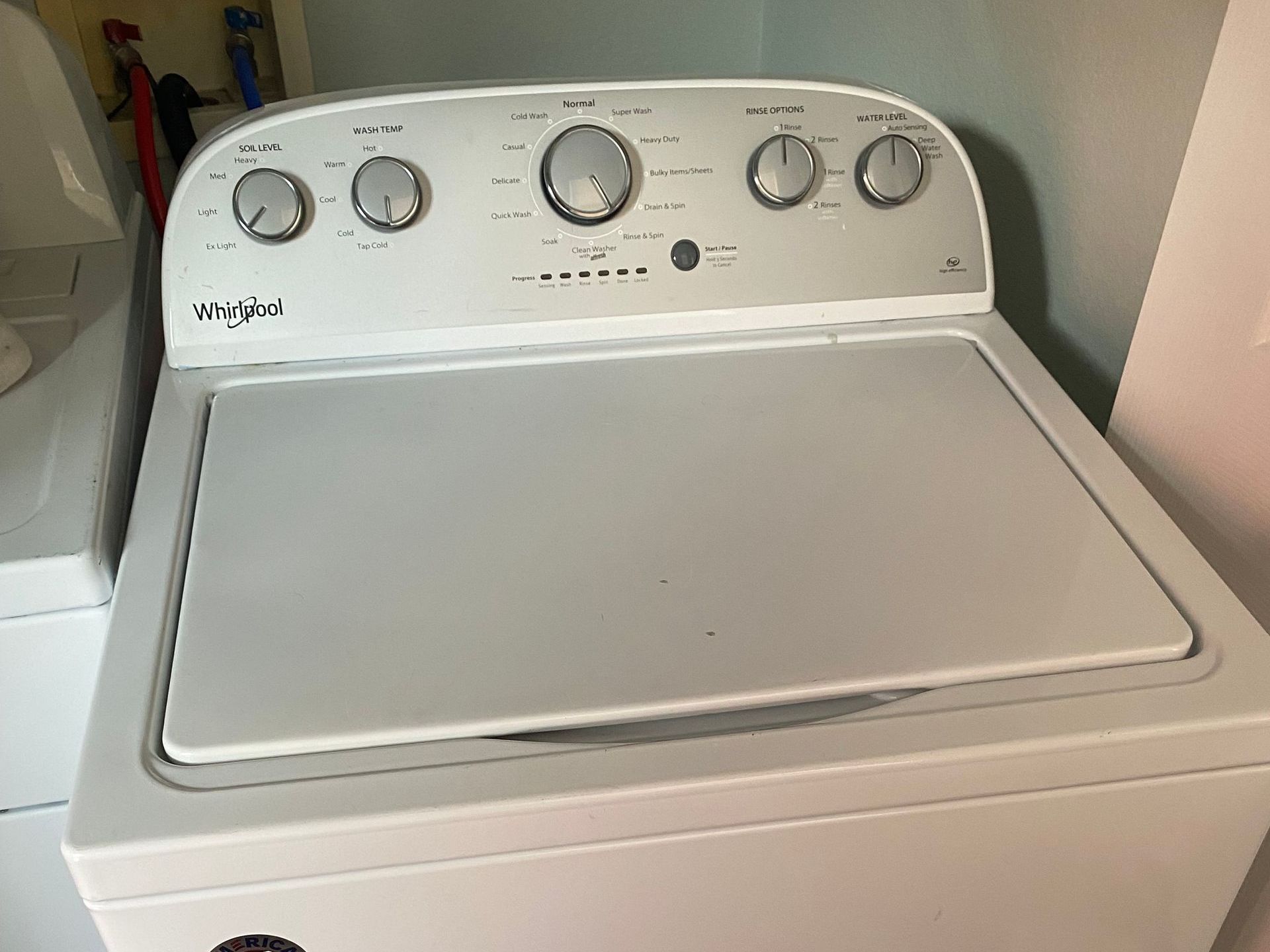 White Whirlpool top-load washing machine with control knobs on top.