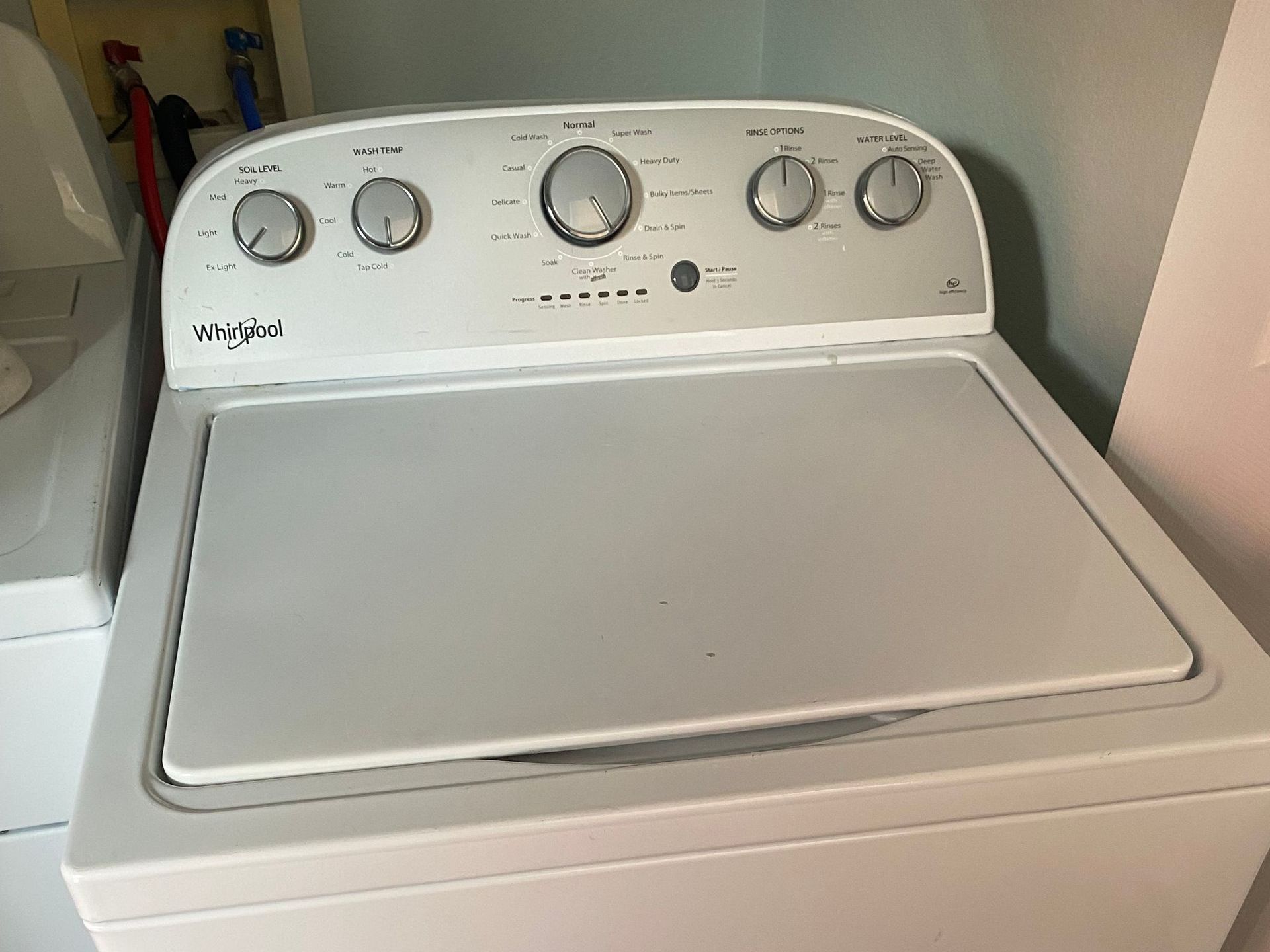 White Whirlpool top-load washing machine in a laundry room.