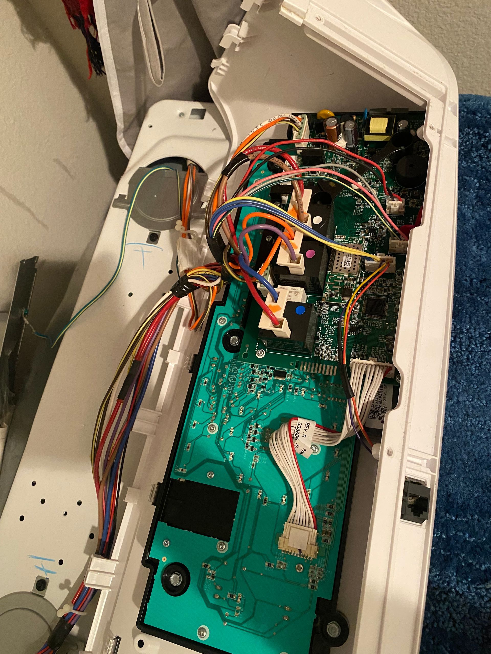Open appliance interior showing circuit boards and colored wires.