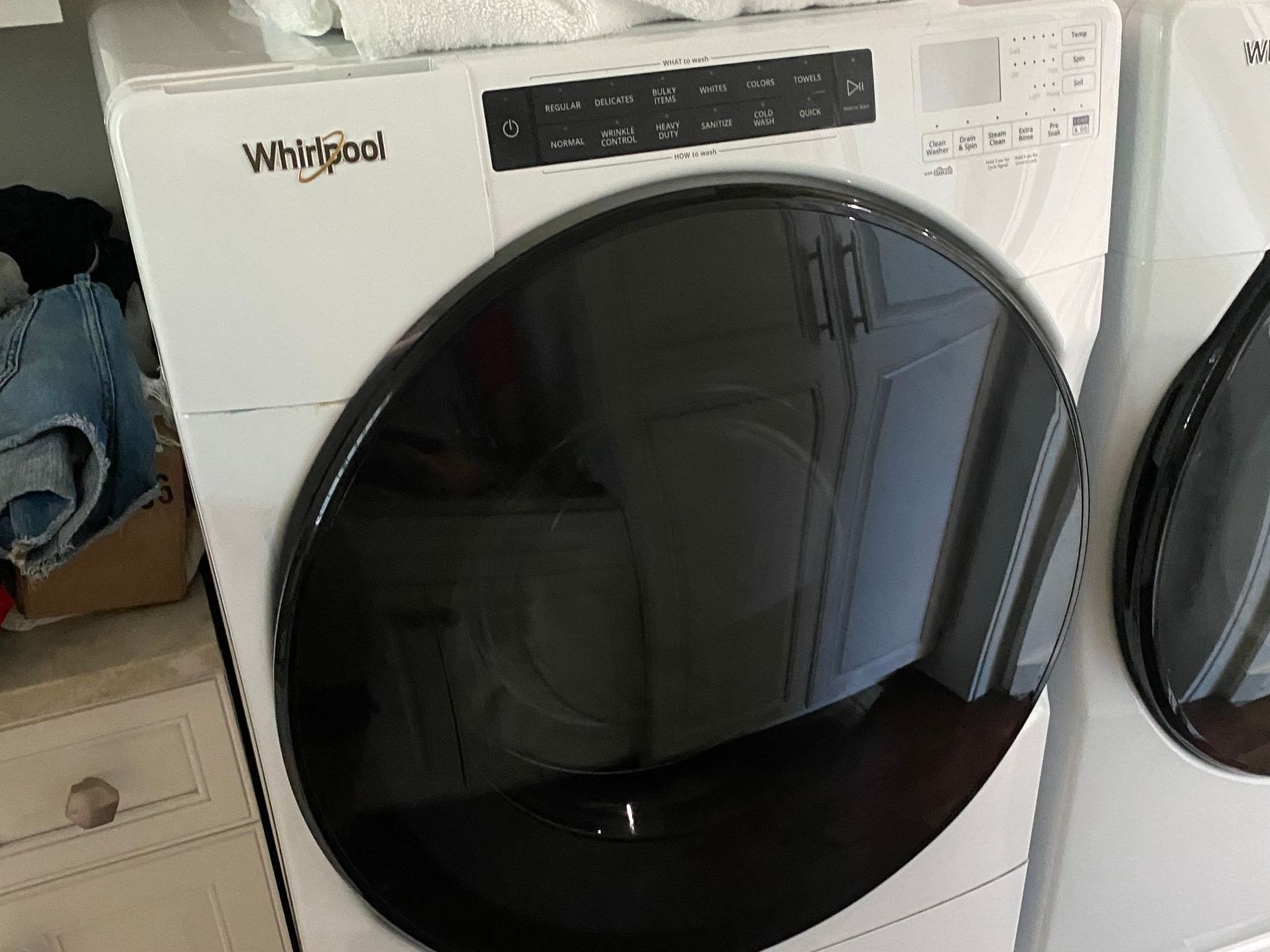 White Whirlpool dryer with black door, in a laundry room.