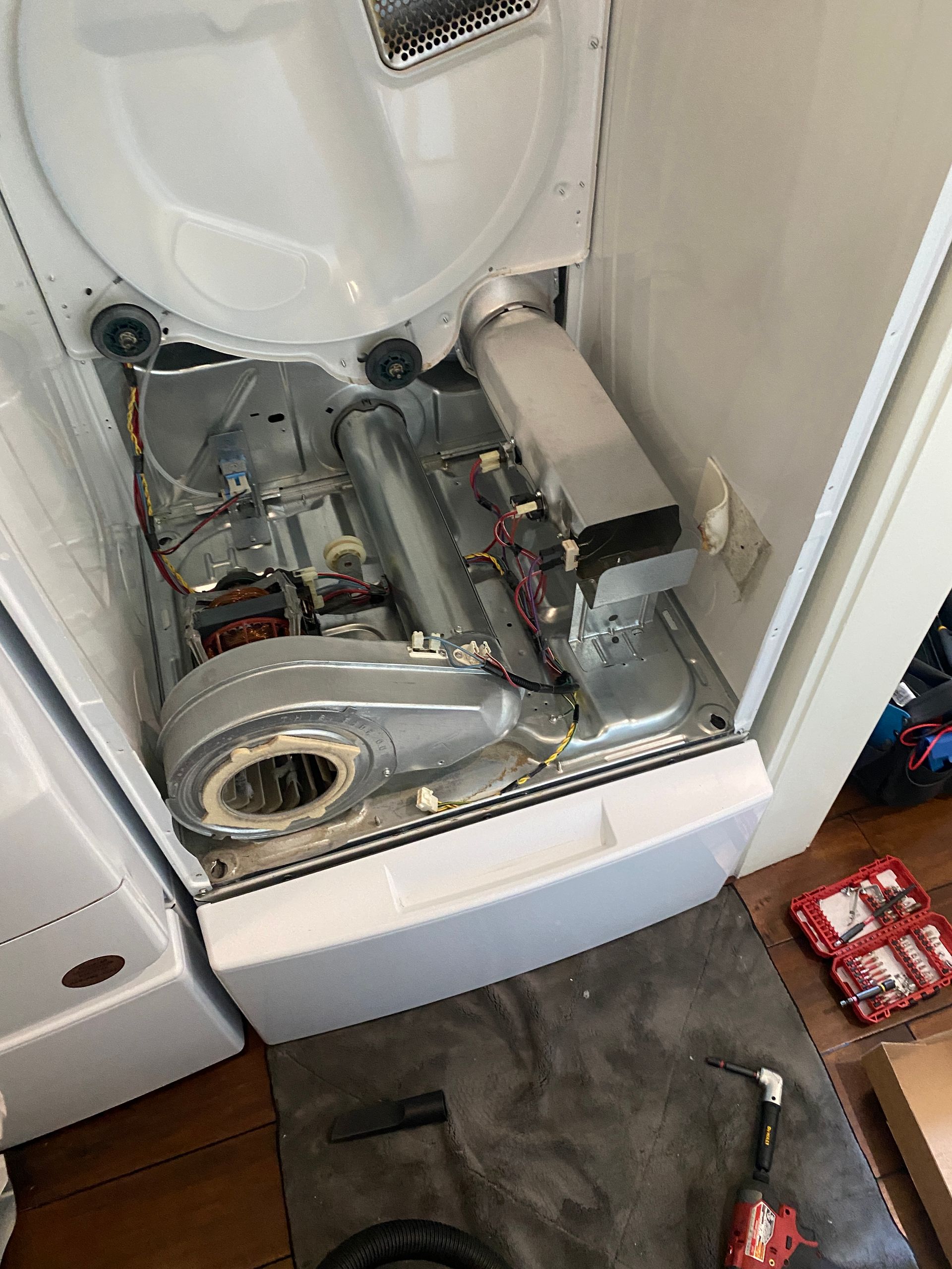 Open dryer showing internal components: blower, heating element, vent system, and various wires.