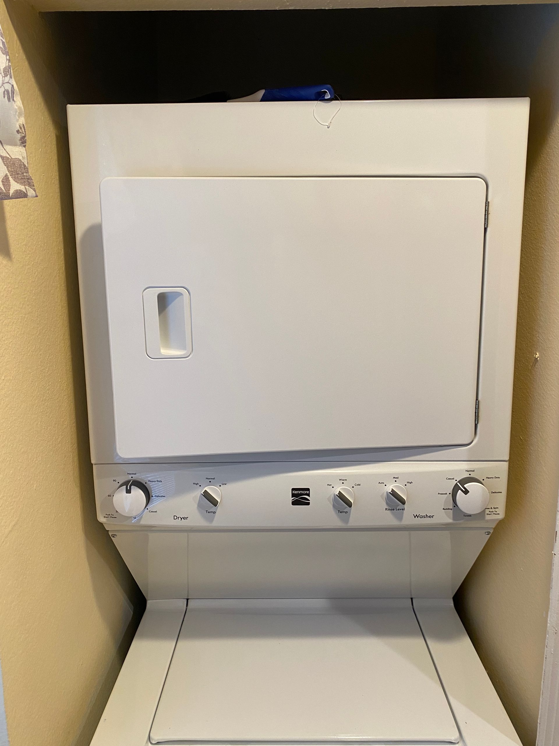 Stacked white Kenmore washer and dryer unit, front view in a small alcove.