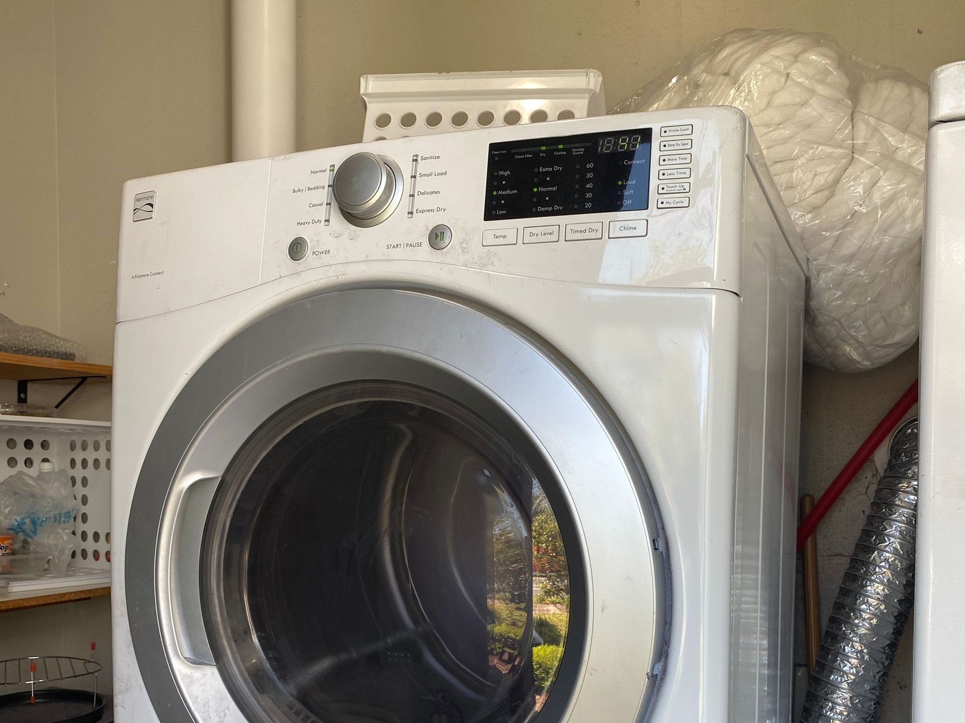 White Kenmore dryer in a laundry room, with a basket on top.
