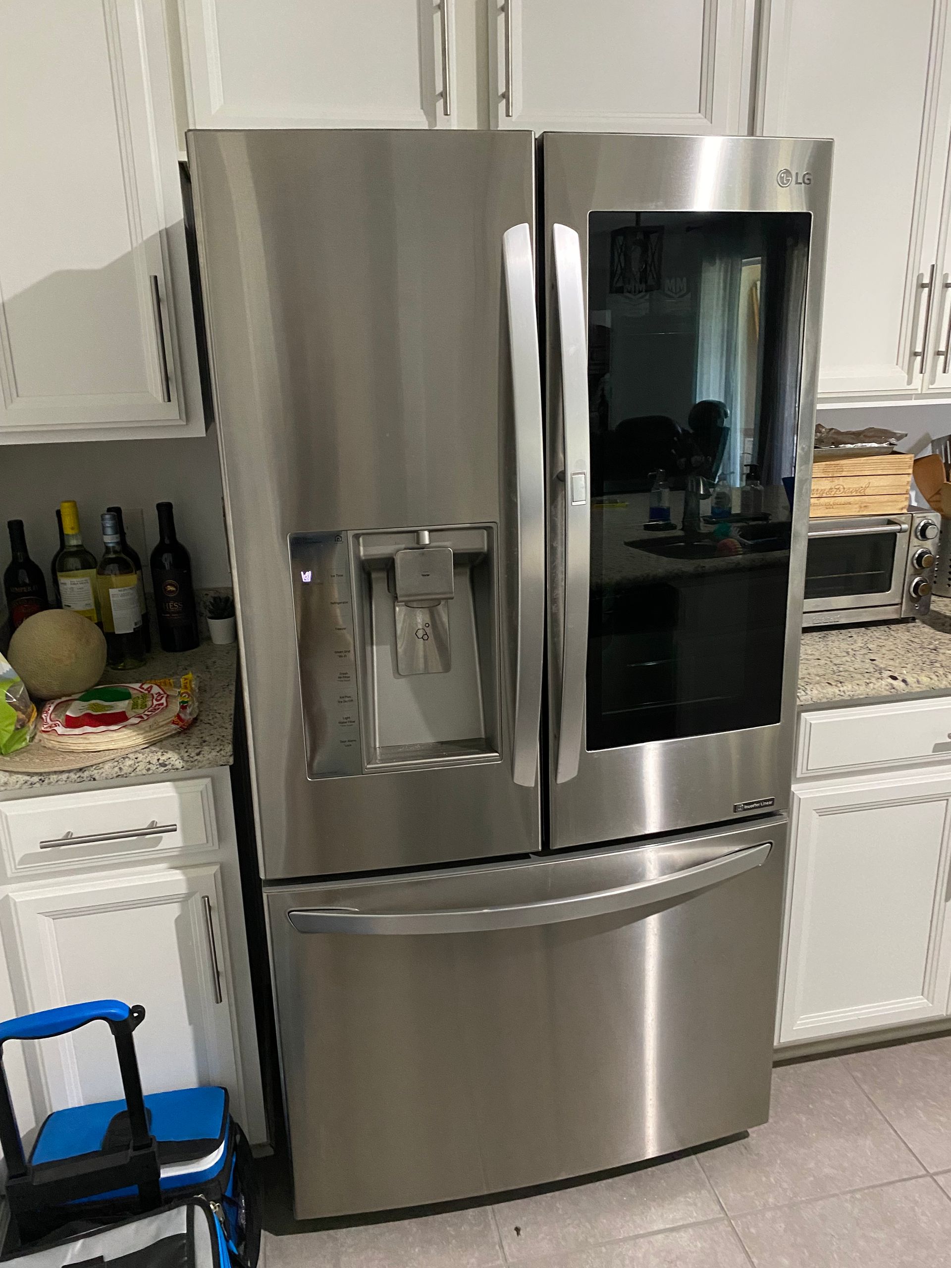 Stainless steel LG refrigerator in a kitchen with white cabinets.