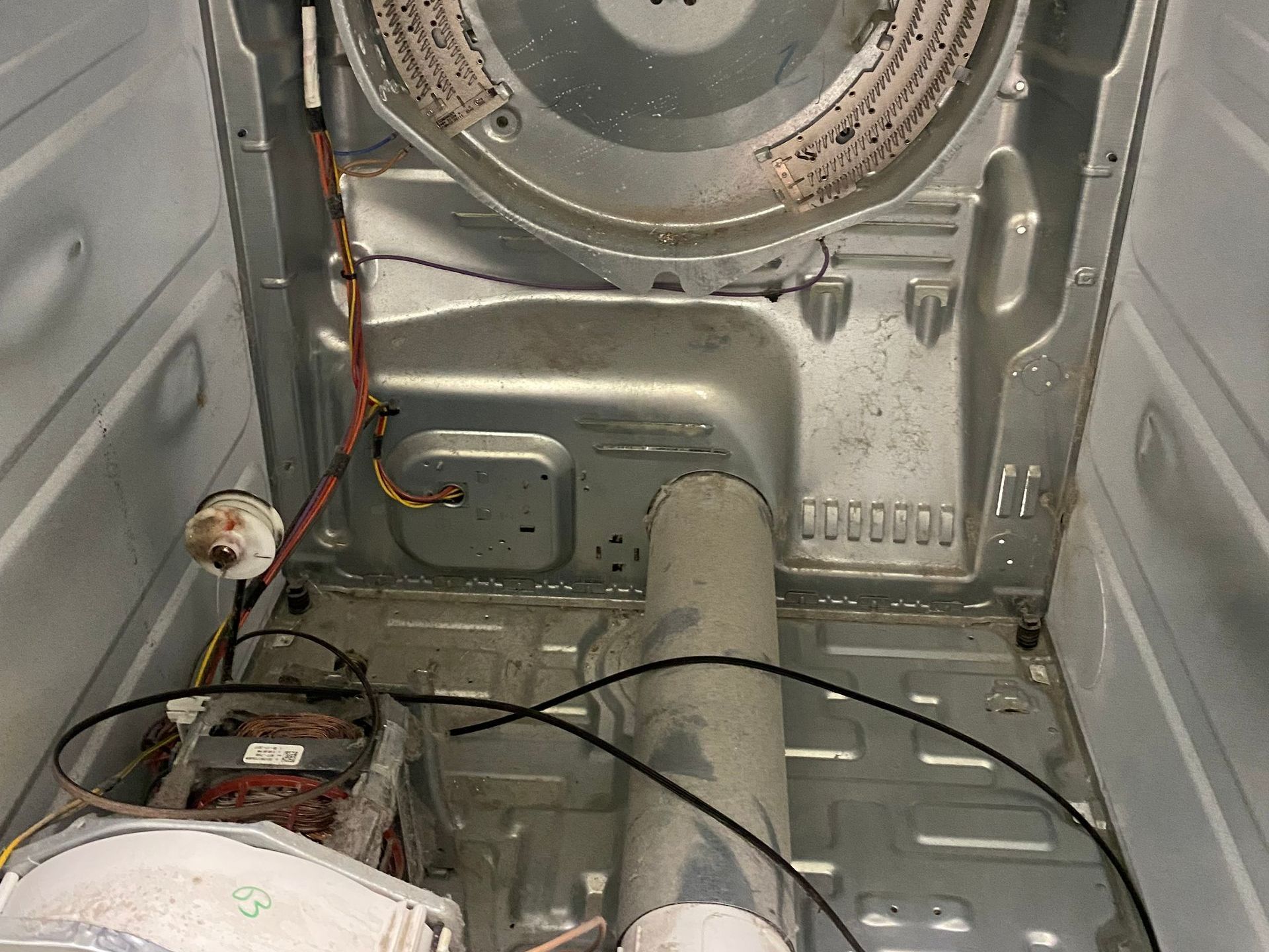 Interior of a dryer with the back panel removed. Visible components: heating element, motor, and vent.