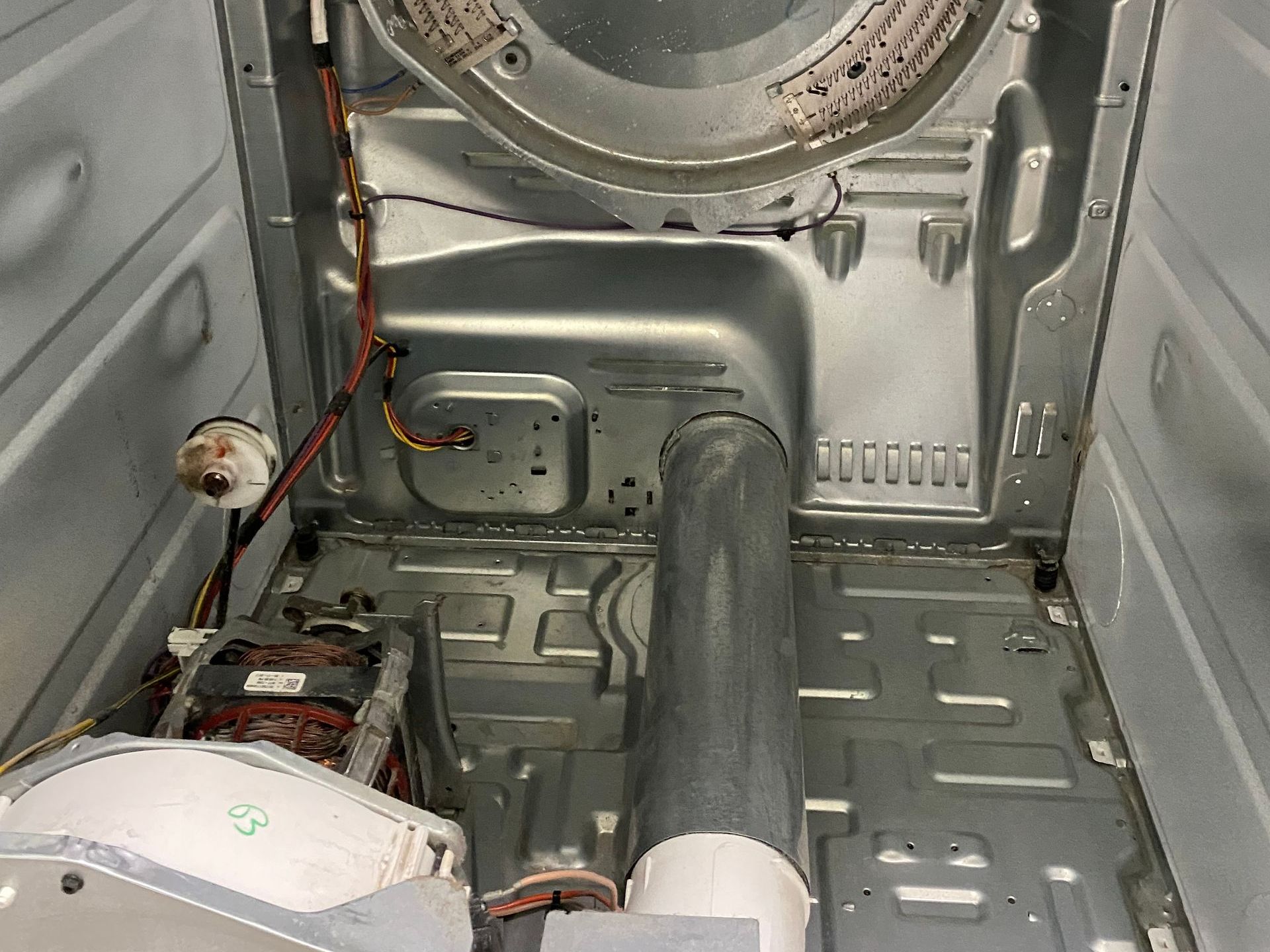 Interior view of a disassembled dryer with metal components, a motor, and a vent.
