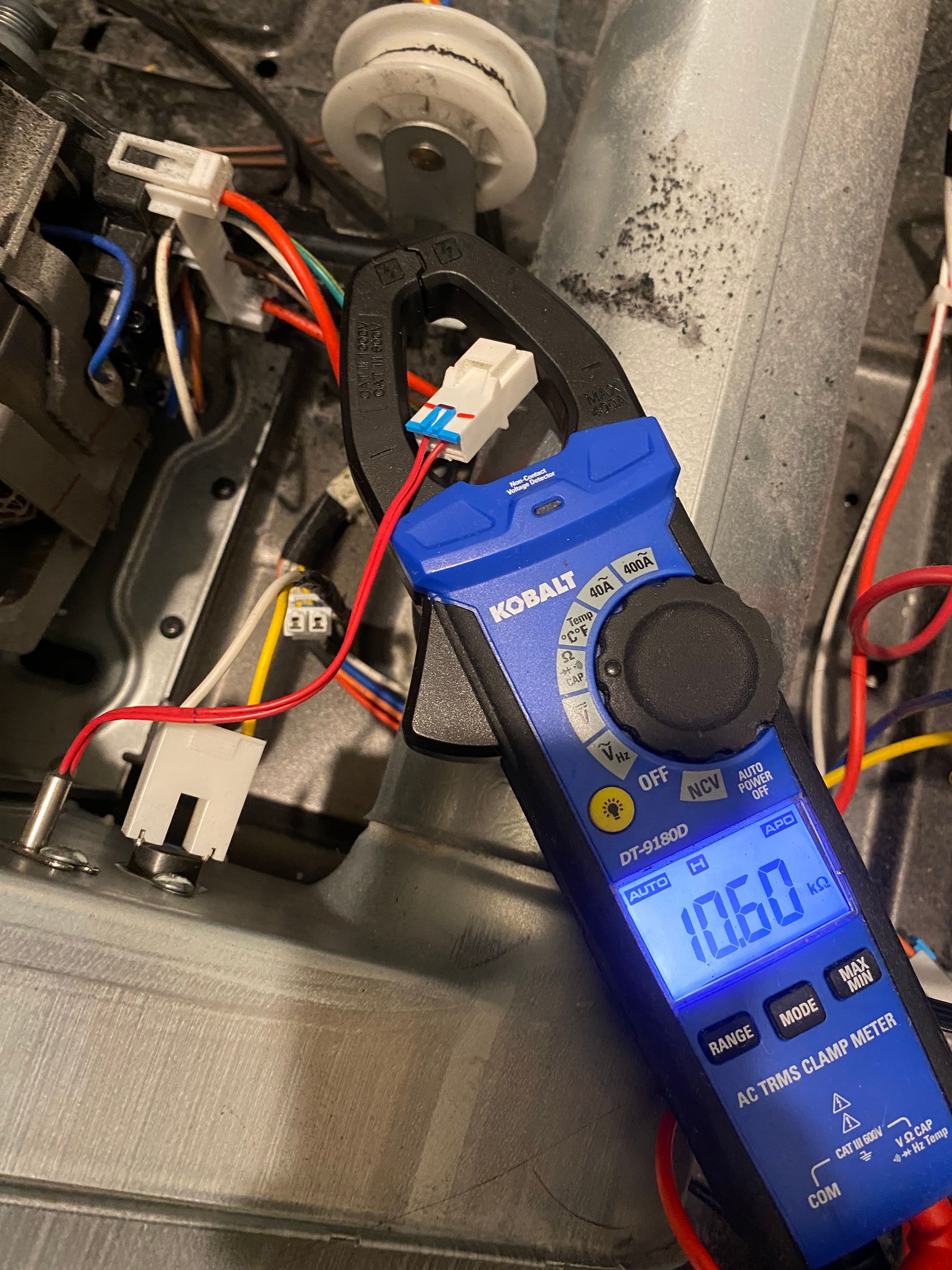 Blue clamp meter measuring 10.60 amps on a dryer wire connector. Interior shot.