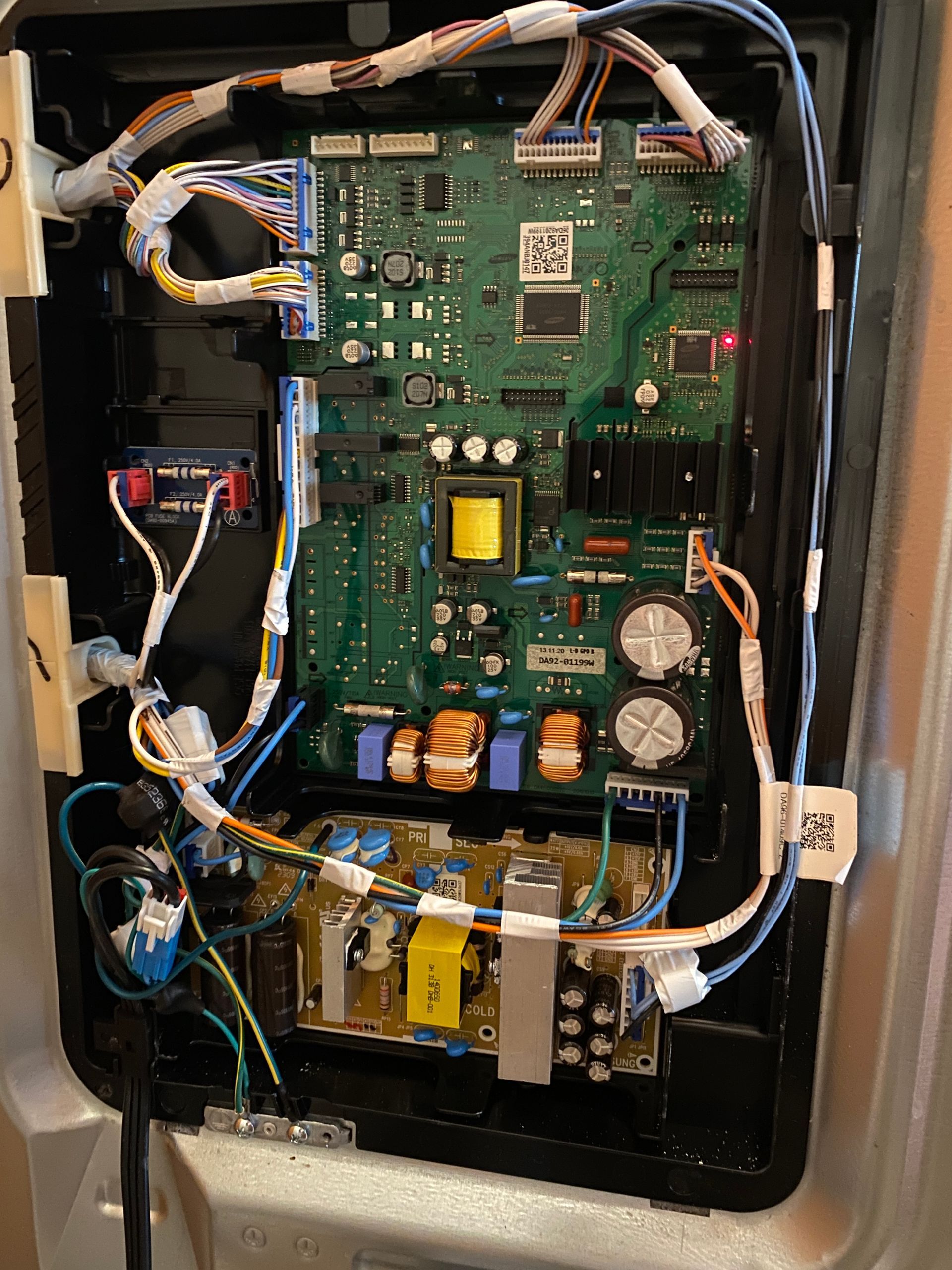 Electronic circuit board assembly inside a refrigerator with various components and wiring.