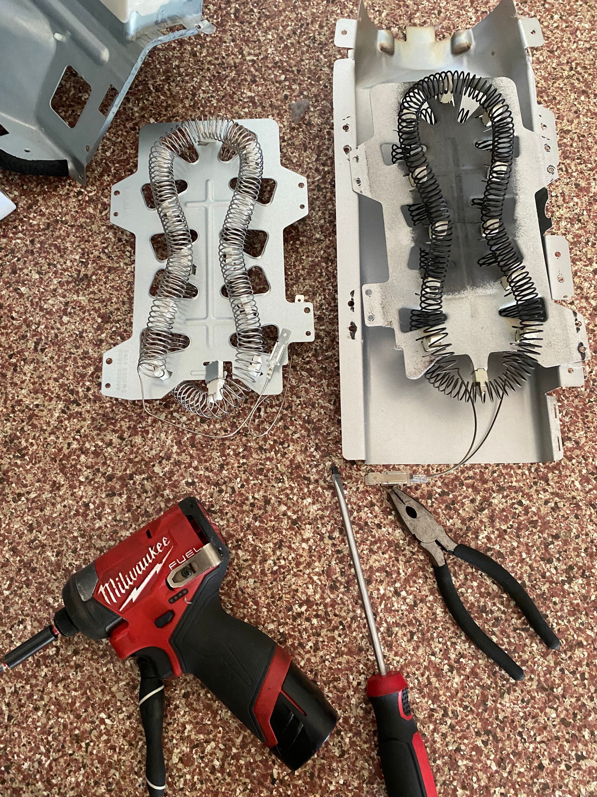 Two dryer heating elements with tools: power drill, screwdriver, and pliers.
