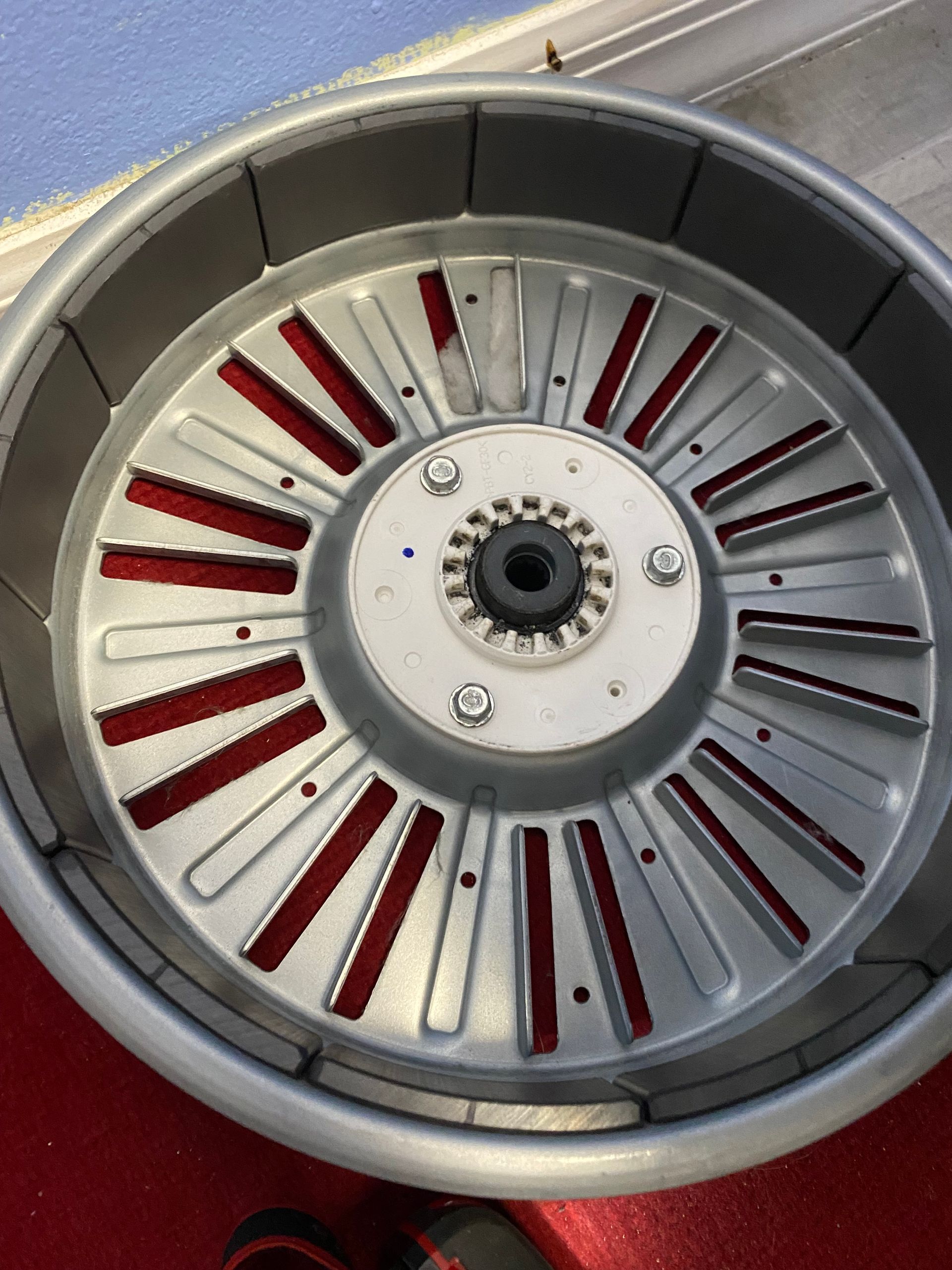 Metallic fan with radial blades and red highlights, likely part of a machine or engine.