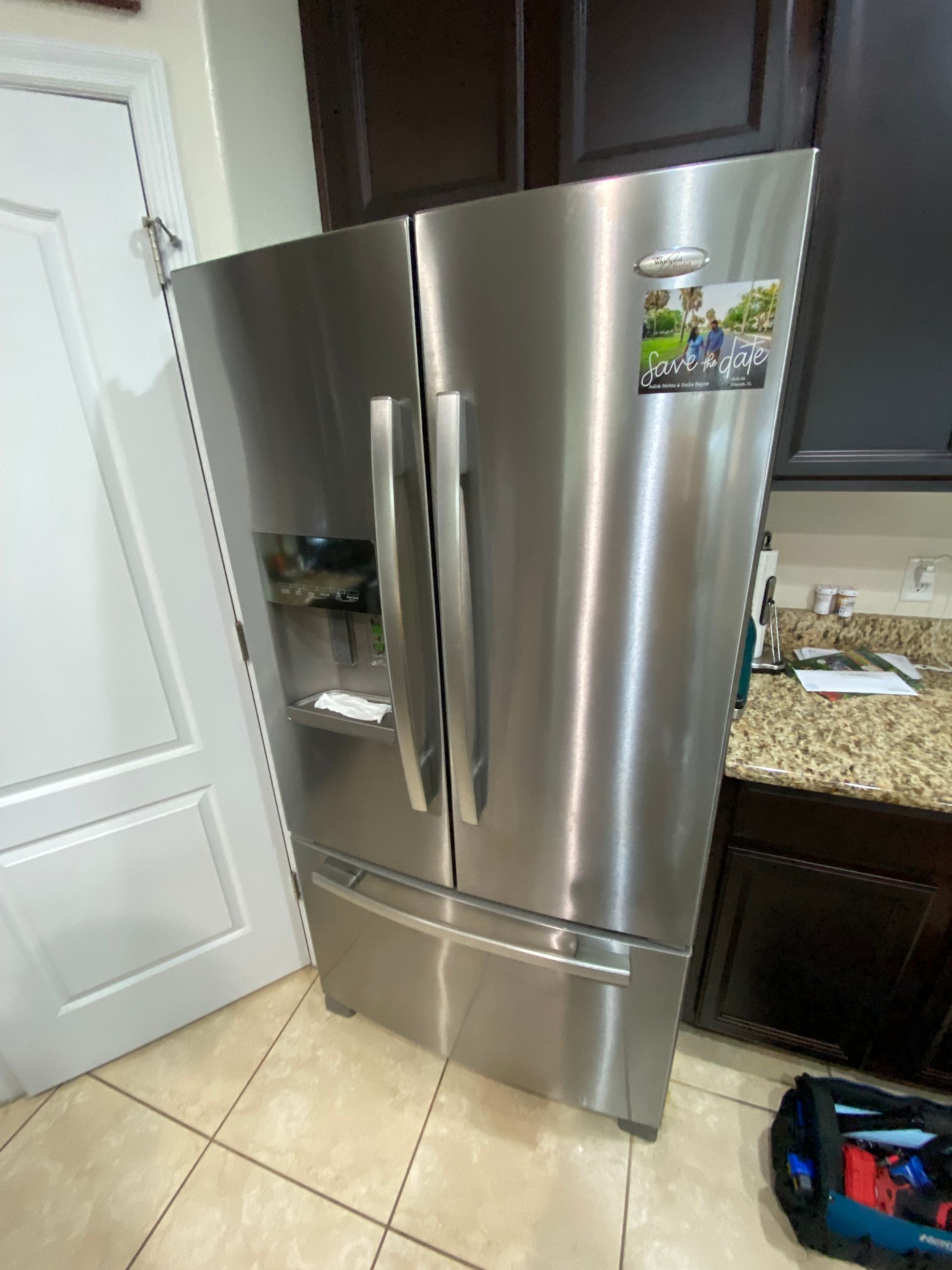 Stainless steel refrigerator in a kitchen setting; side-by-side doors, bottom freezer.