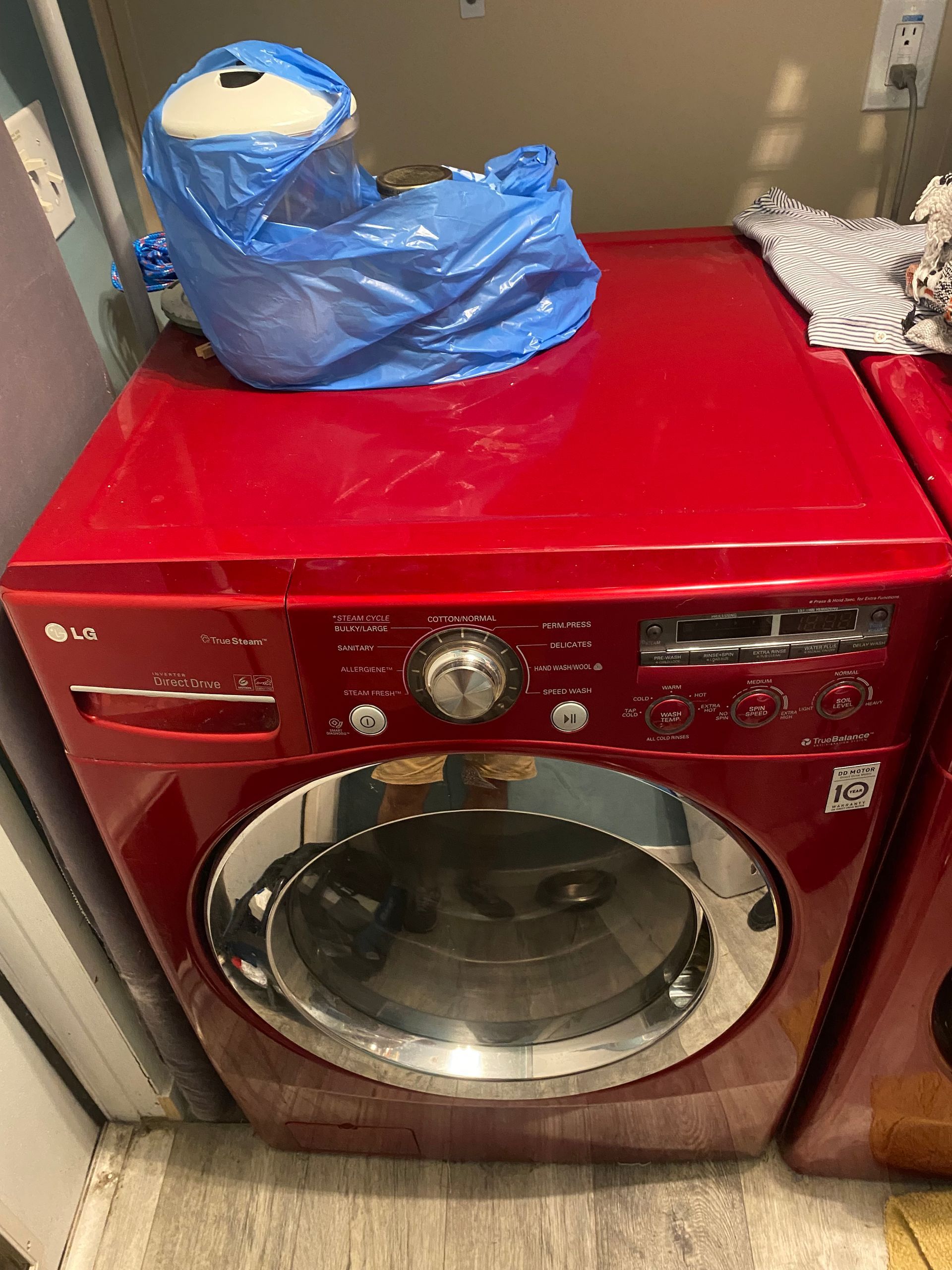 Red LG washing machine with blue bag on top.