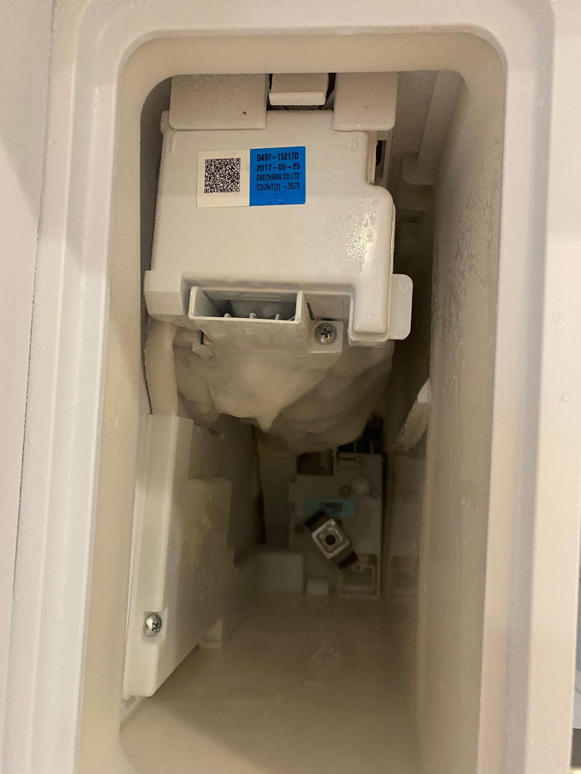 Interior view of a white washing machine dispenser with a detergent compartment and various mechanical components.