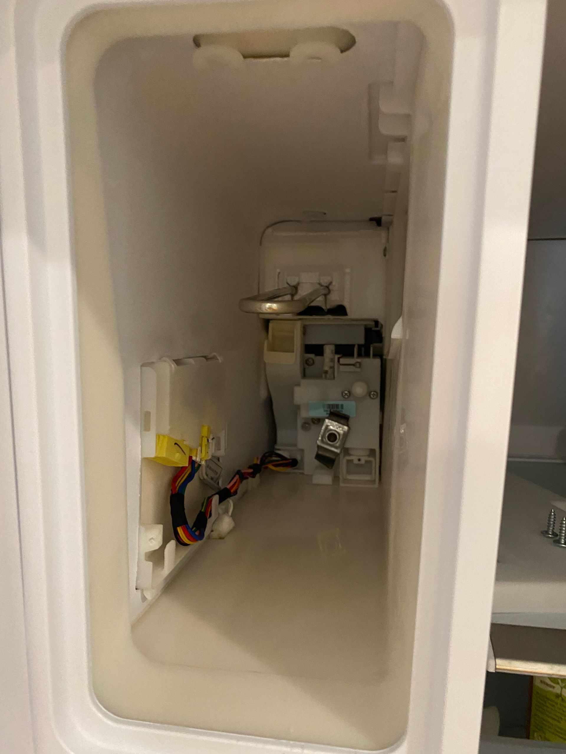 Interior of a refrigerator door compartment showing components and electronic parts. White plastic with varying shapes.