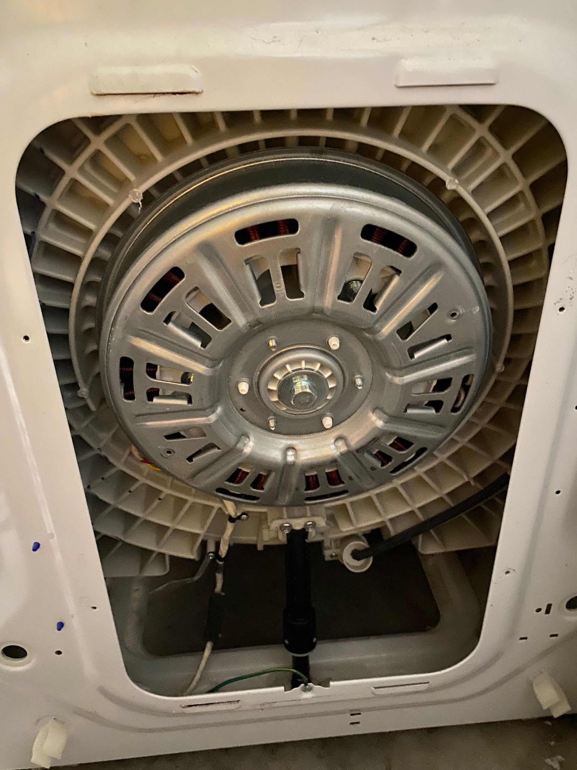 A washing machine's interior with a large circular motor at the center. White plastic housing.