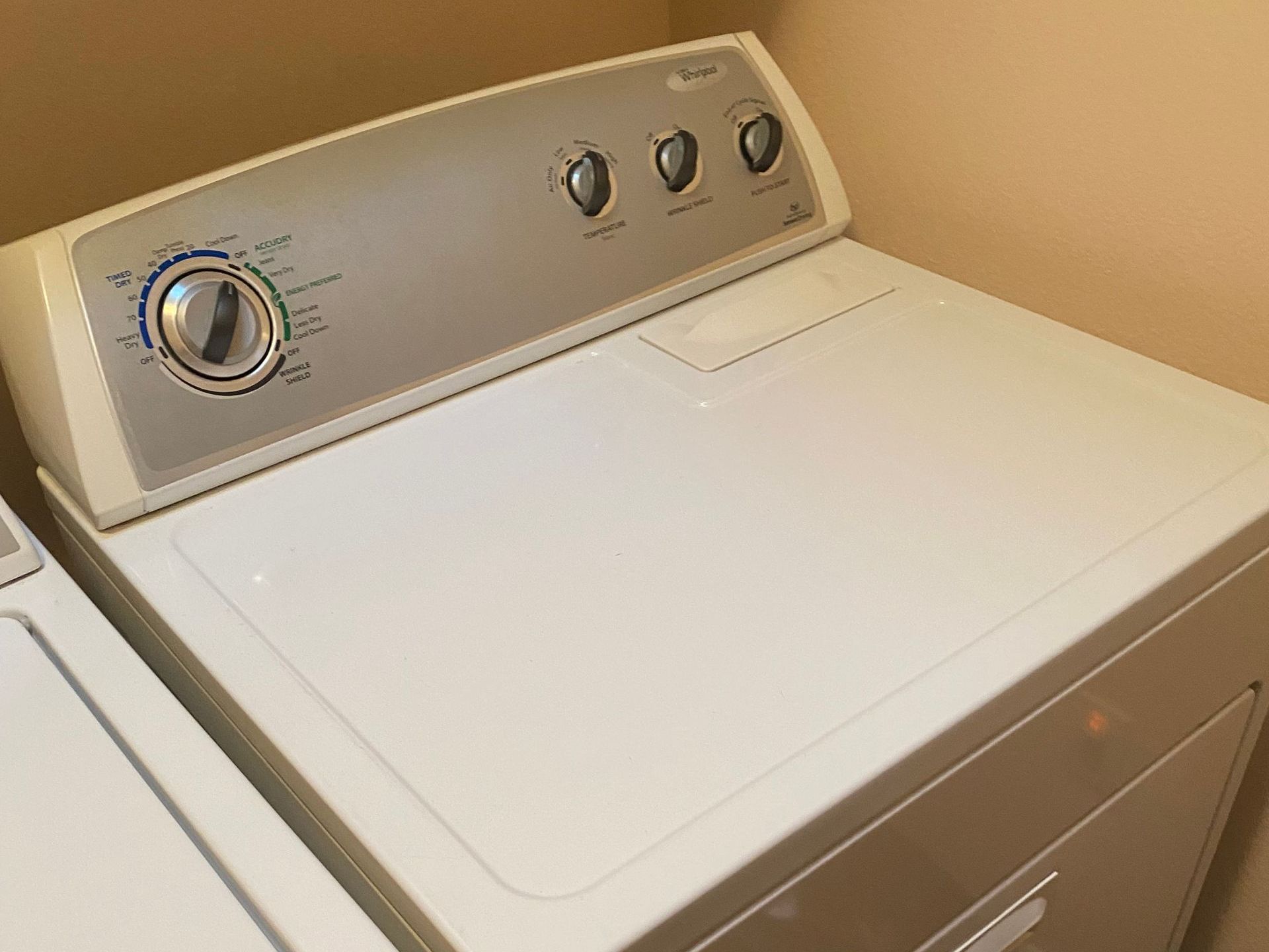 White clothes dryer with silver control panel, dials, and a top-loading door.