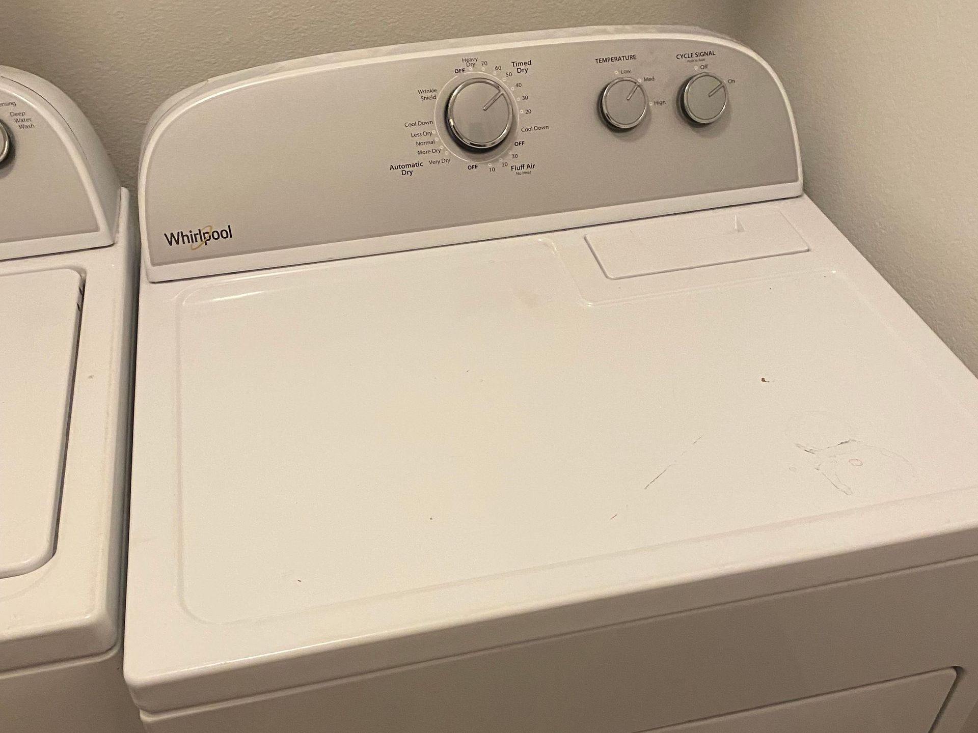 White Whirlpool dryer with control knobs on top.