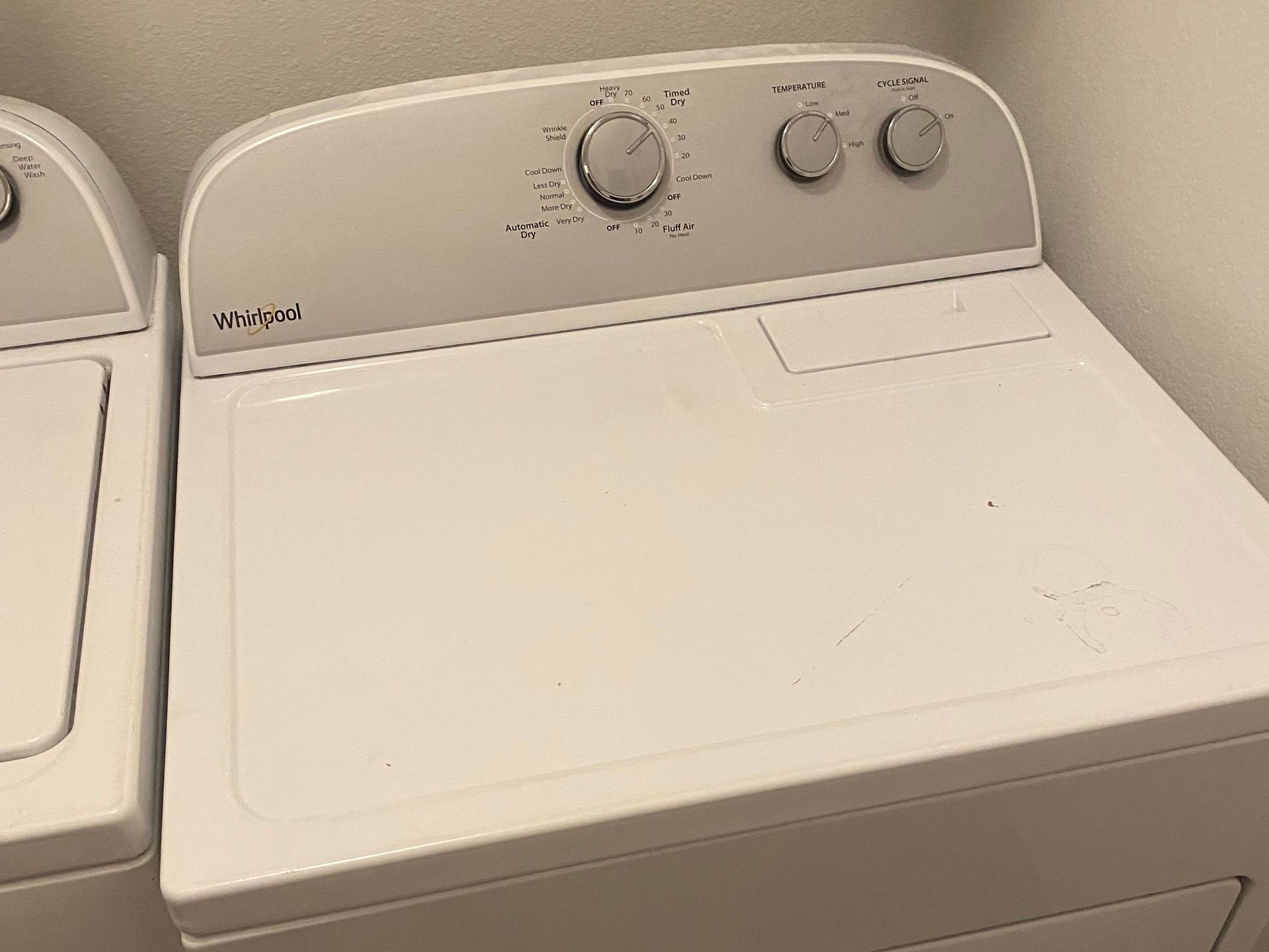 White Whirlpool dryer with control knobs on top.