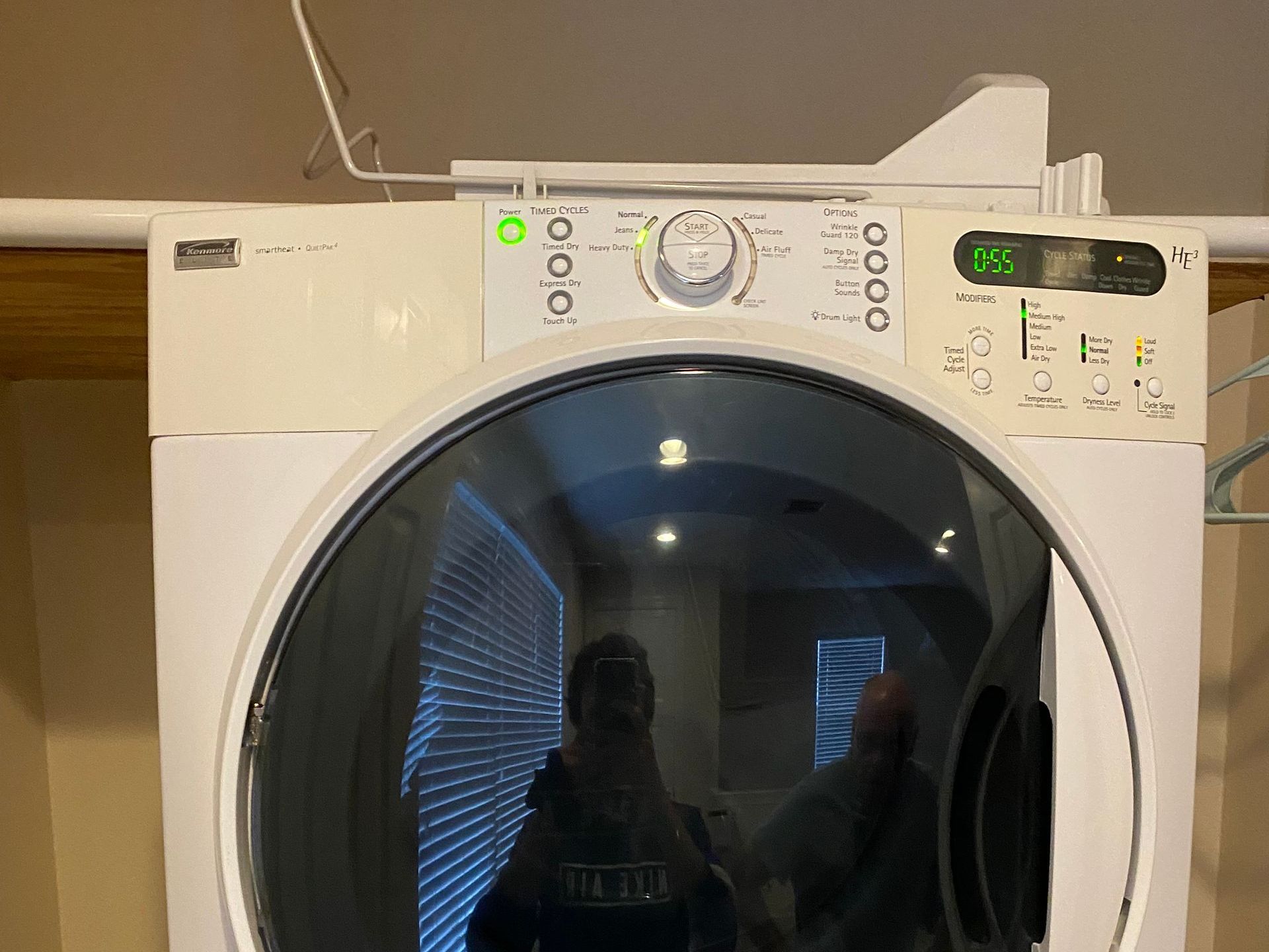 White Kenmore dryer with control panel, glass door, and green light illuminated.
